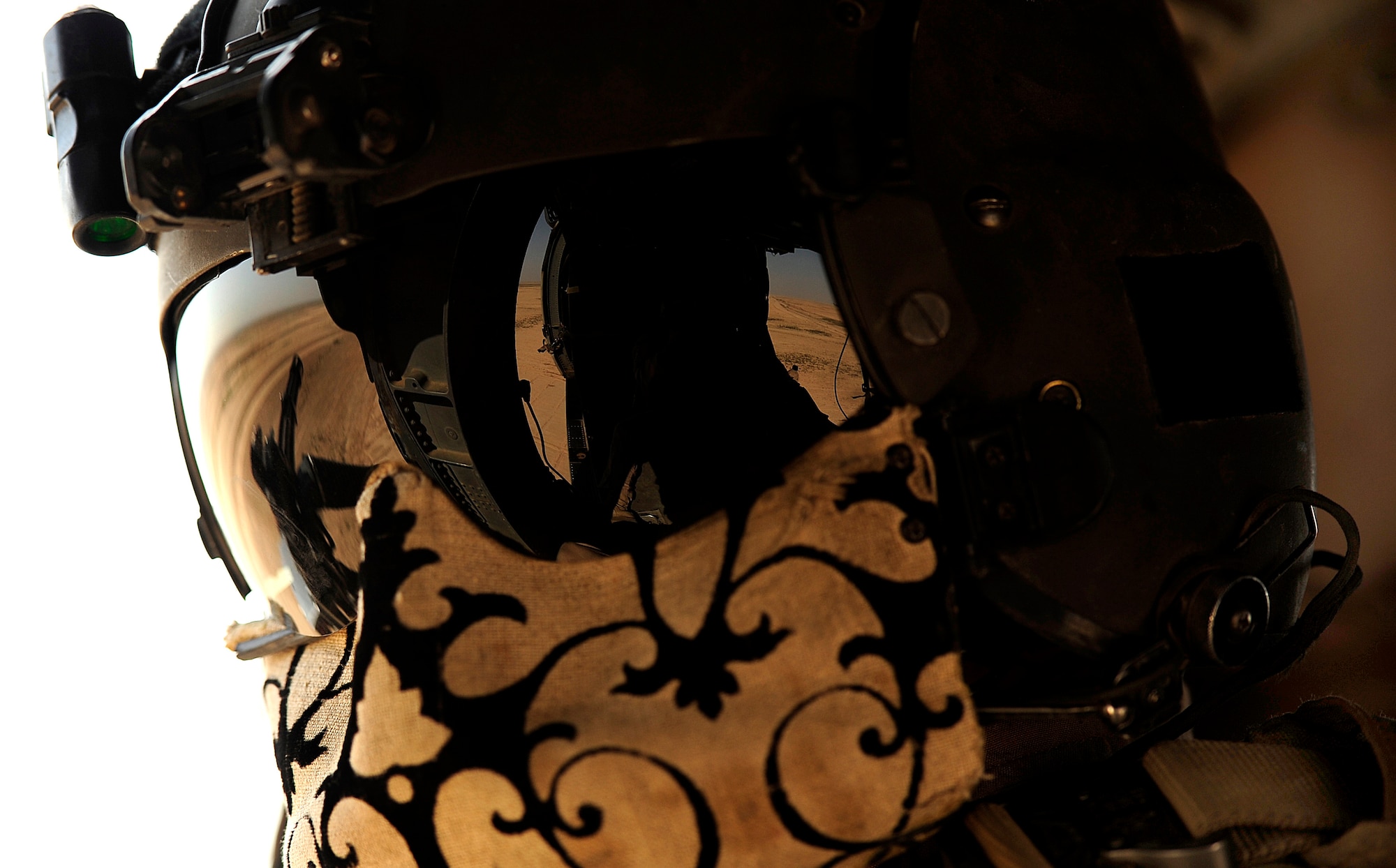 U.S. Air Force Staff Sgt. Andrew Pena, an HH-60G PaveHawk aerial gunner assigned to the 64th Expeditionary Rescue Squadron, secures his protective gear from the heat at his gunner’s window during a flying mission at Joint Base Balad, Iraq, July 12, 2010. (U.S. Air Force photo by Staff Sgt. Andy M. Kin / Released)