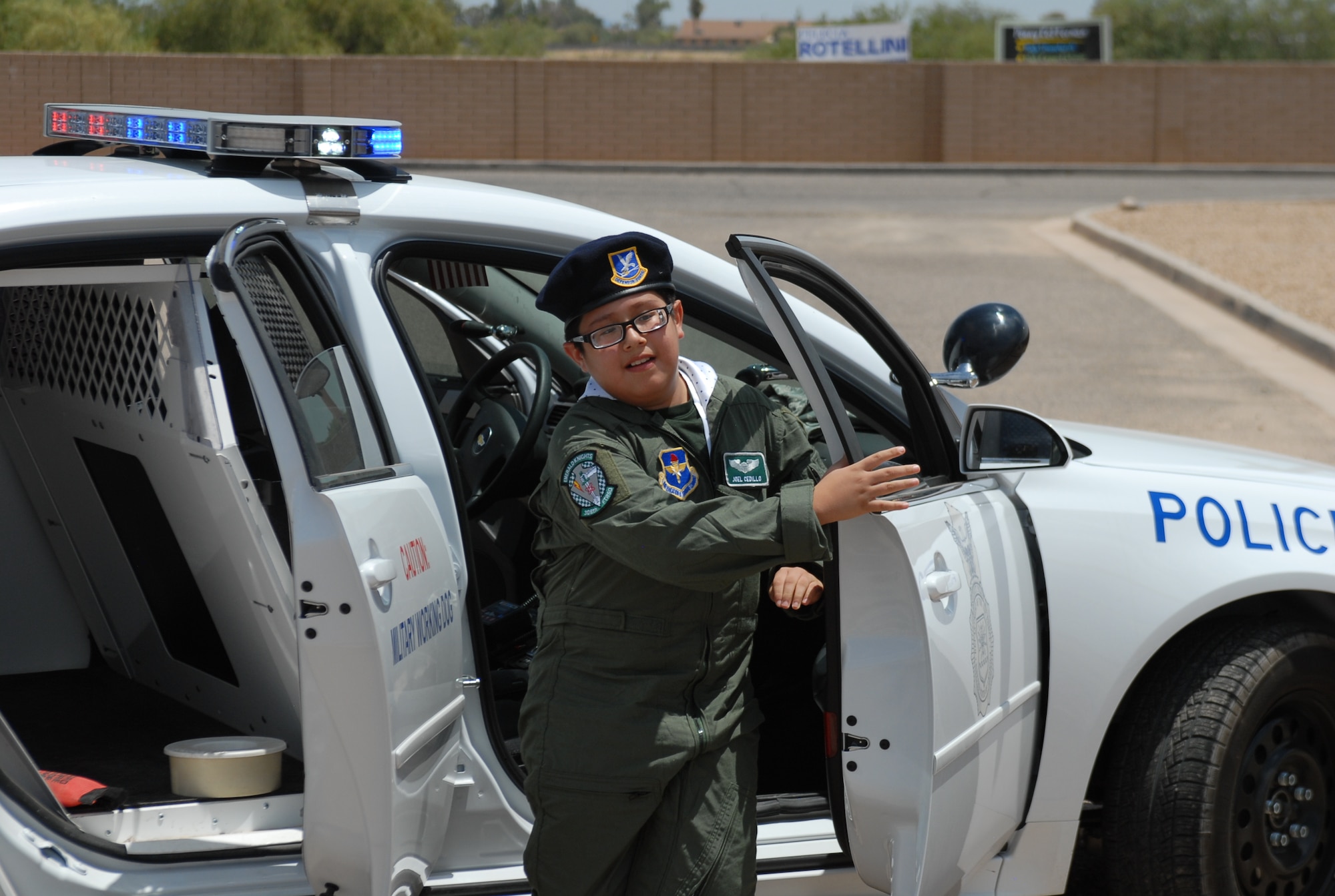 Joel "Burner" Cedillo, 10, hurries out of a police car to stop a "bad guy" during a simulated working dog demonstration held at the Luke Air Force Base softball fields during a pilot-for-a-day visit on July 16th.  (U.S. Air Force photo/Airman 1st Class Sandra Welch)