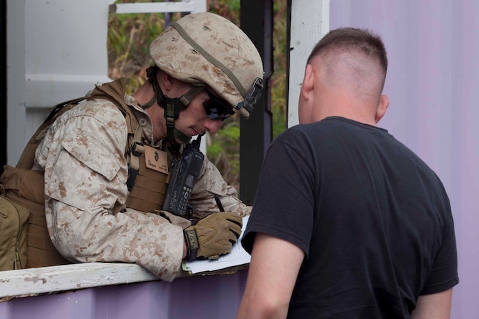 Lance Cpl. J. M. Candrian, a U.S. Marine assigned to 2nd Battalion, 3rd Marine Regiment, checks in a U.S. citizen role player outside a mock embassy during a noncombatant evacuation operation at Marine Corps Training Area Bellows, Hawaii, July 26. The NEO, an emergency evacuation involving the use of military forces and capabilities in order to provide aid, assistance and movement to safety of American citizens overseas, was conducted as part of interoperability training between coalition forces during the multi-national Exercise Rim of the Pacific 2010.