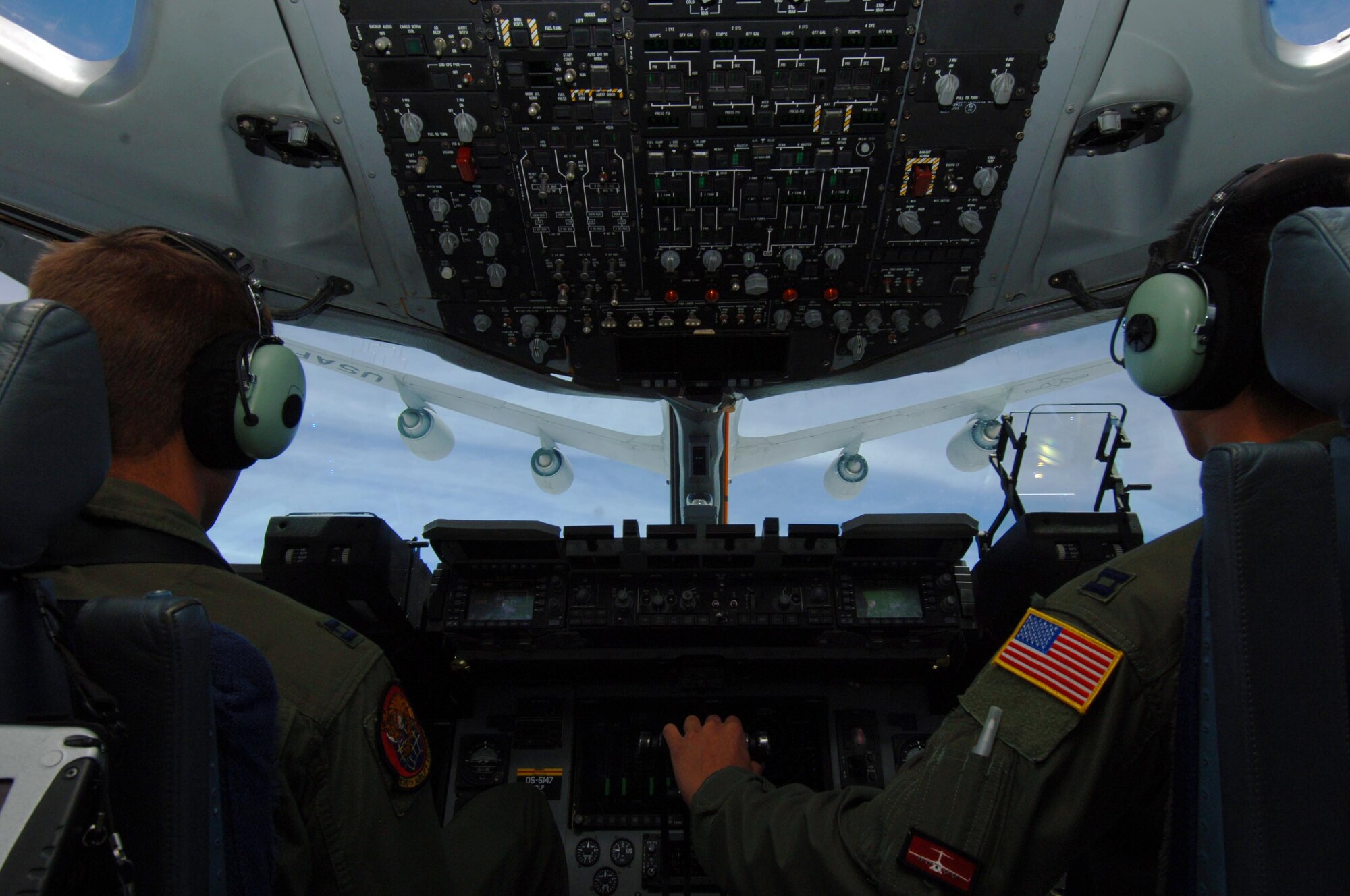 From left: Capt. Brandon Dewey and Capt. Jon Ma, 535th Airlift Squadron pilots, watch as a KC-135 from the Ohio Air National Guard make its approach to refuel a C-17 July 23. The sortie the C-17 flew included a simulated cargo drop, in-flight refueling, and participation in a simulated fire fight as part of a Rim of the Pacific exercise. (U.S. Air Force photo by Staff Sgt. Nathan Allen)