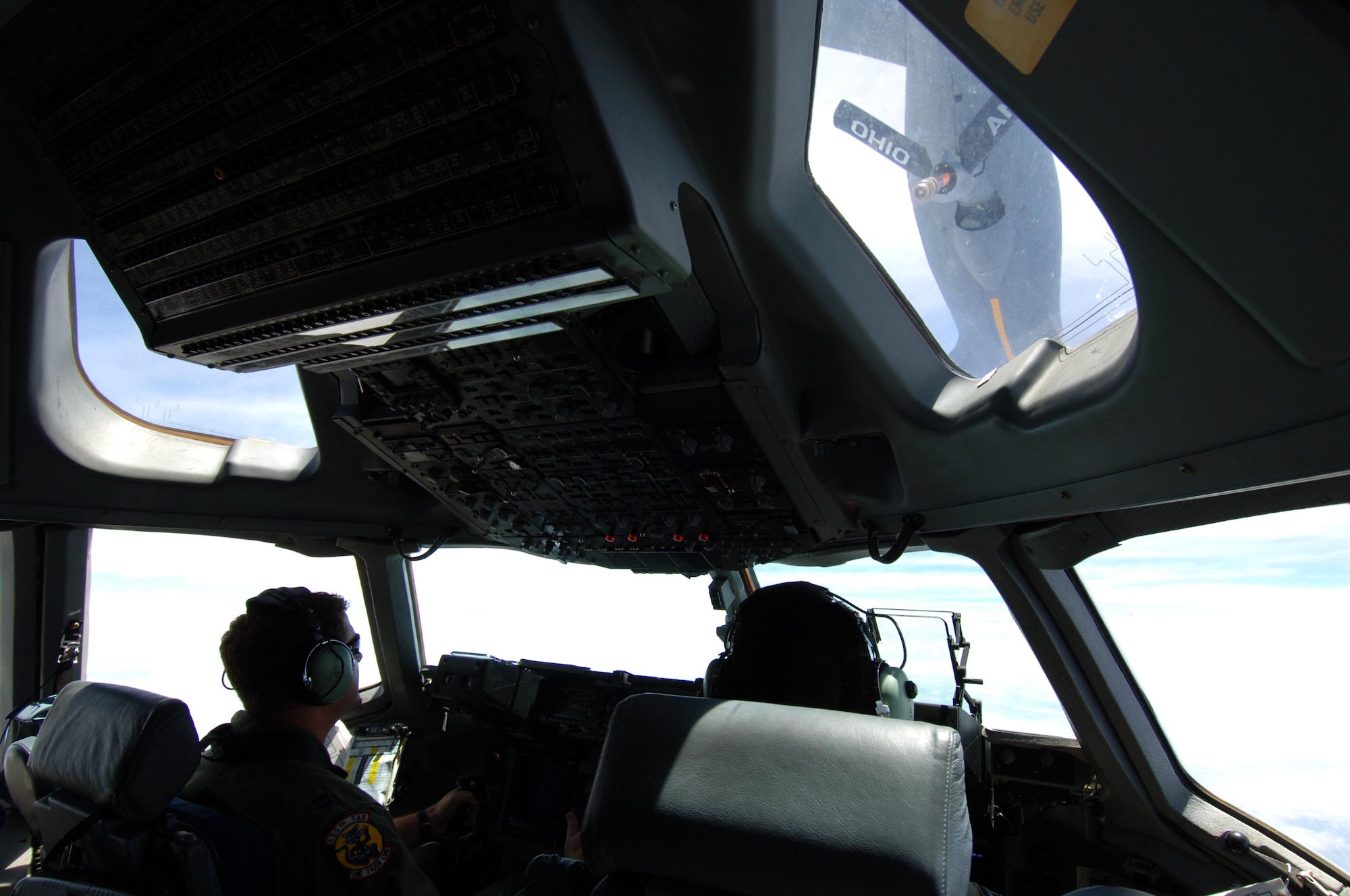 From left: Capt. Alan Partridge and Capt Jon Ma, 535th Airlift Squadron pilots, watch as a KC-135 from the Ohio Air National Guard make its approach to refuel a C-17 July 23. The sortie the C-17 flew included a simulated cargo drop, in-flight refueling, and participation in a simulated fire fight as part of a Rim of the Pacific exercise. (U.S. Air Force photo by Staff Sgt. Nathan Allen)
