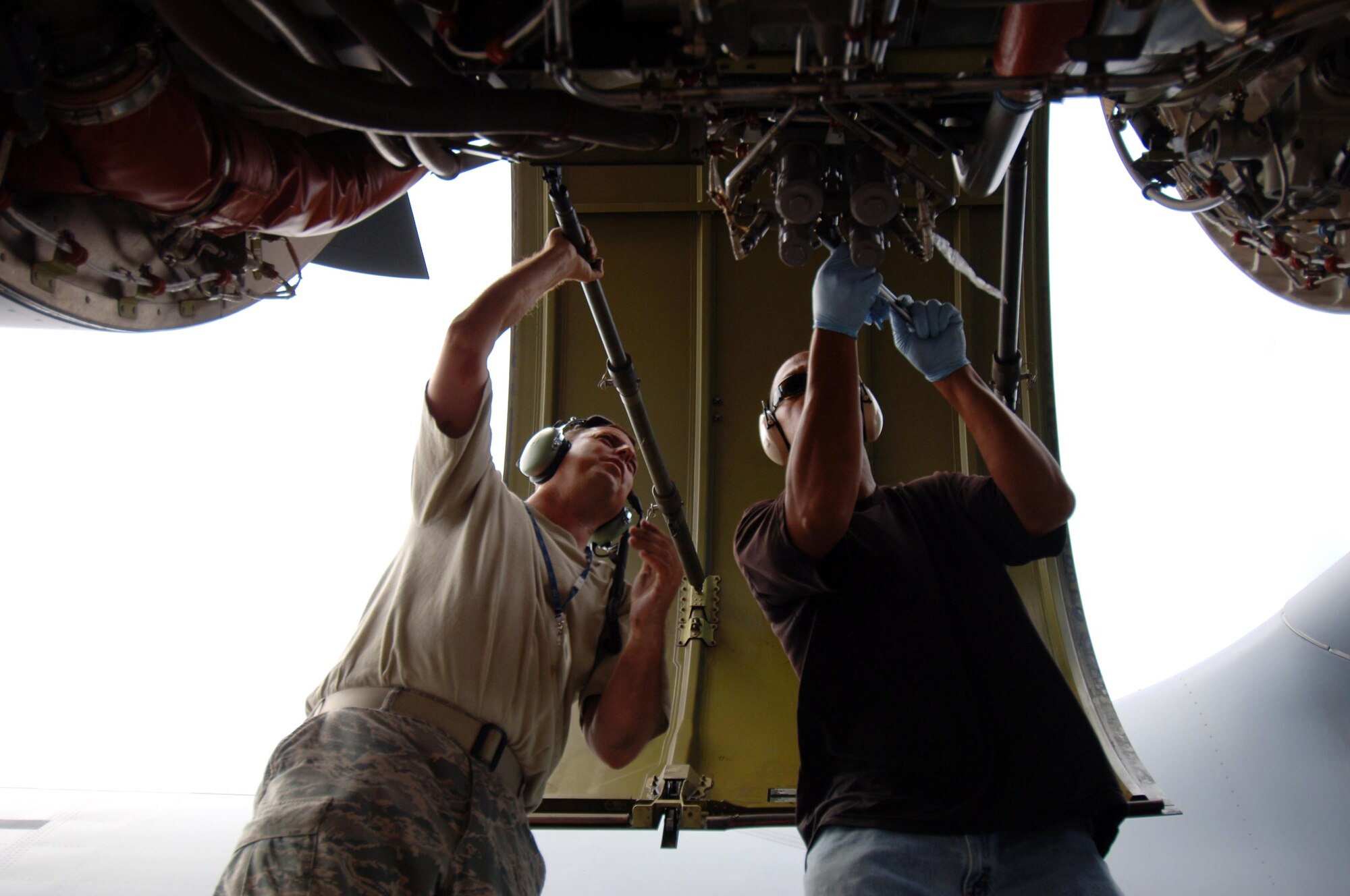 From right: Staff Sgt. El Rey Santiago, 154th Aircraft Maintenance Squadron hydraulics craftsman, and Tech. Sgt. Jason Liosi, 15th Aircraft Maintenance Squadron hydraulics craftsman perform maintenance on the hydraulics system of a C-17 engine July 23. The sortie this aircraft flew included a simulated cargo drop, in-flight refueling, and participation in a simulated fire fight as part of a Rim of the Pacific exercise. (U.S. Air Force photo by Staff Sgt. Nathan Allen)
