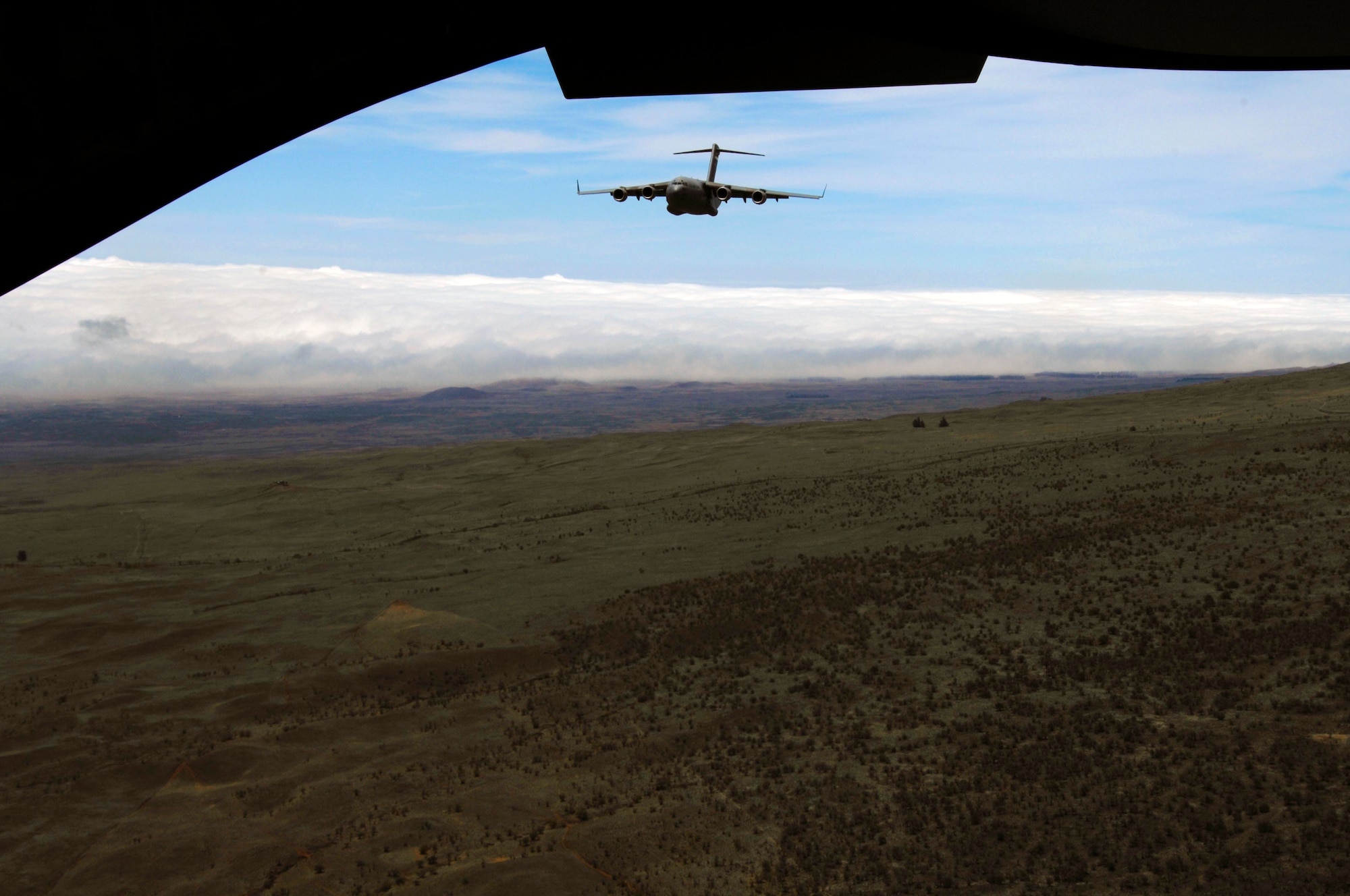 A C-17 flies as part of a two-ship formation over the island of Hawai'i in preparation for low-altitude flying maneuvers July 23. The sortie the lead aircraft flew included a simulated cargo drop, in-flight refueling, and participation in a simulated fire fight as part of a Rim of the Pacific exercise. (U.S. Air Force photo by Staff Sgt. Nathan Allen)
