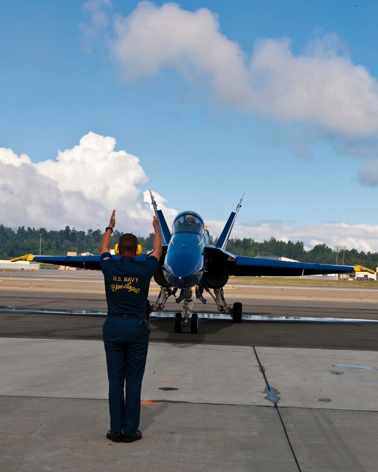 JOINT BASE ELMENDORF RICHARDSON, Alaska -- U.S. Navy Blue Angels crew member marshals in a pilot after arriving at Joint Base Elmendorf-Richardson July 27. The Blue Angels will be one of the main performances during this year?s Arctic Thunder Air Show, taking place July 31 and Aug. 1. Gates open at 9 a.m. and parking and admission are free. (Air Force photo by Airman 1st Class Jack Sanders)