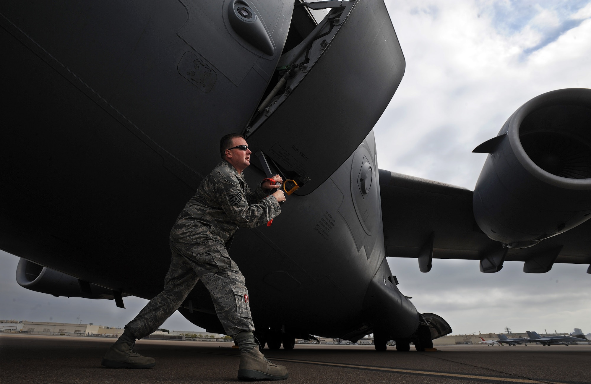Tech. Sgt. Jerry Laughlin, a crew chief from the 452nd Aircraft Maintenance Squadron at March Air Reserve Base, opens the crew entry door of a C-17 Globemaster III, at Naval Air Station North Island, Calif., during the weekly ICMOP
mission.  (U.S. Air Force photo by Master Sgt. Rick Sforza)