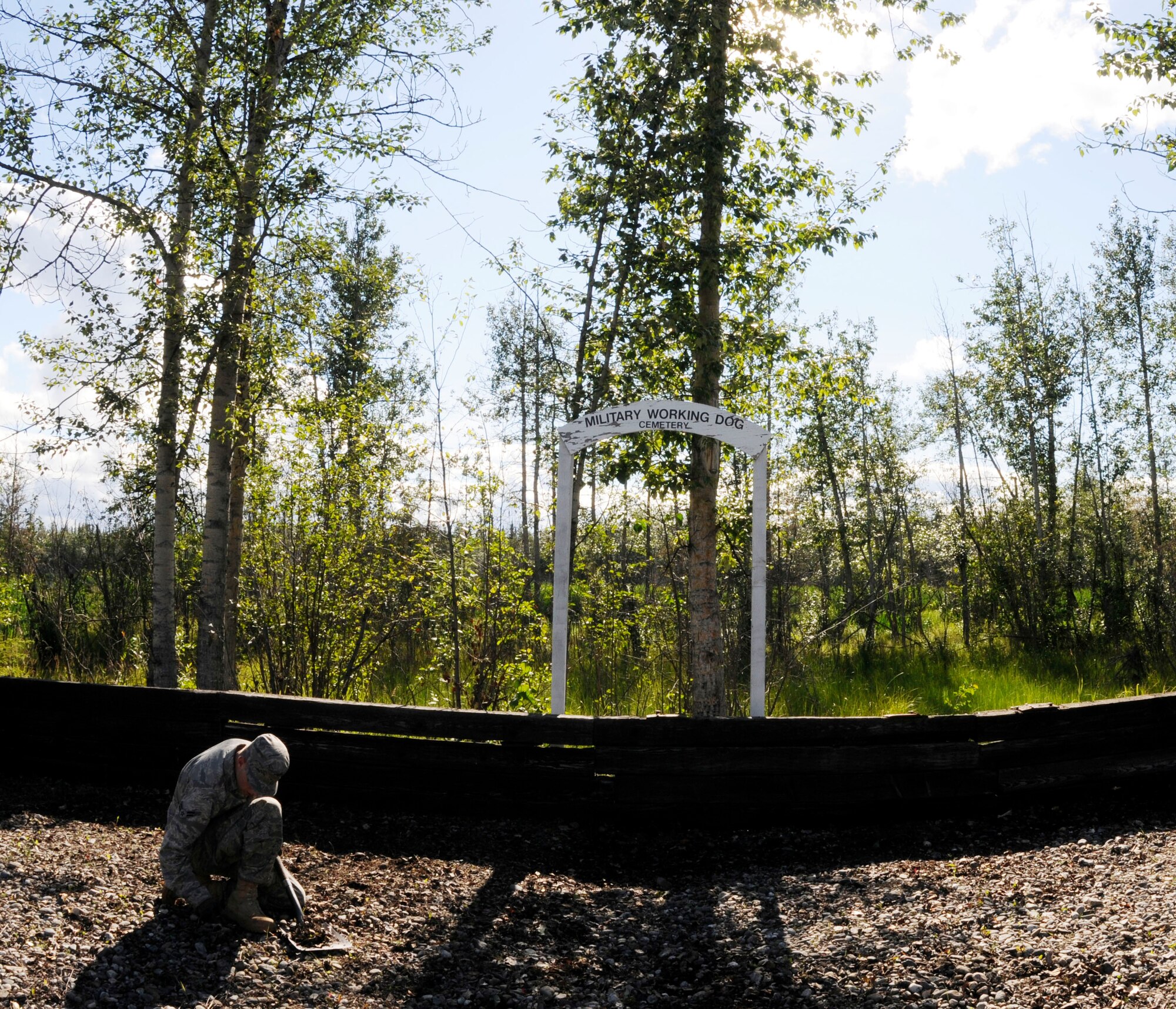 An Airman puts the finishing touches on the clean-up of the Military Working Dog Memorial July 22, 2010,Eielson Air Force Base, Alaska. Airmen weeded and reorganized the memorial to make sure the area reflected appropriate respect for its residents. (Airman 1st Class Yash Rojas)