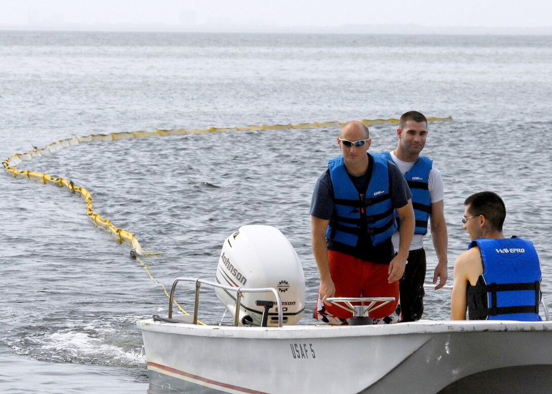 Volunteers bring the towed oil boom into shore prior to installing it along one of many shorelines July 14, 2010, at Eglin Air Force Base, Fla. Boom is an oil containment device used to trap oil in the water so it can be collected before reaching the shore.. (U.S. Air Force photo/Samuel King Jr.) 