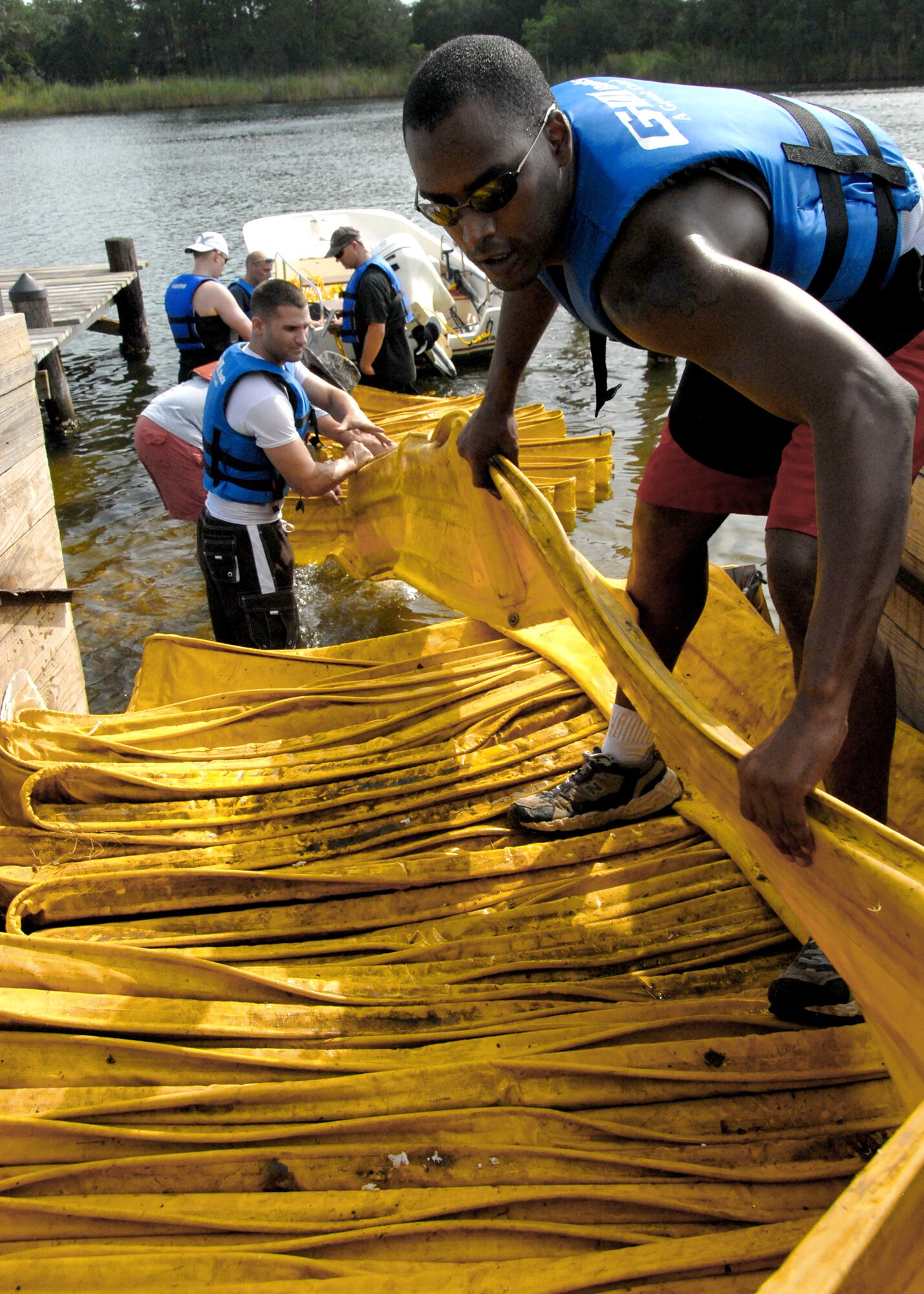 Staff Sgt. Adam Elerson (right) and Airman 1st Class Brian Beauchamp pull boom out of a trailer July 14, 2010, at Eglin Air Force Base, Fla., where 600 feet of boom was used to protect the shoreline. Boom is an oil containment device used to trap oil in the water so it can be collected before reaching the shore. Seregeant Elerson and Airman Beauchamp are members of the 96th Aerospace Medicine Squadron. (U.S. Air Force photo/Samuel King Jr.)