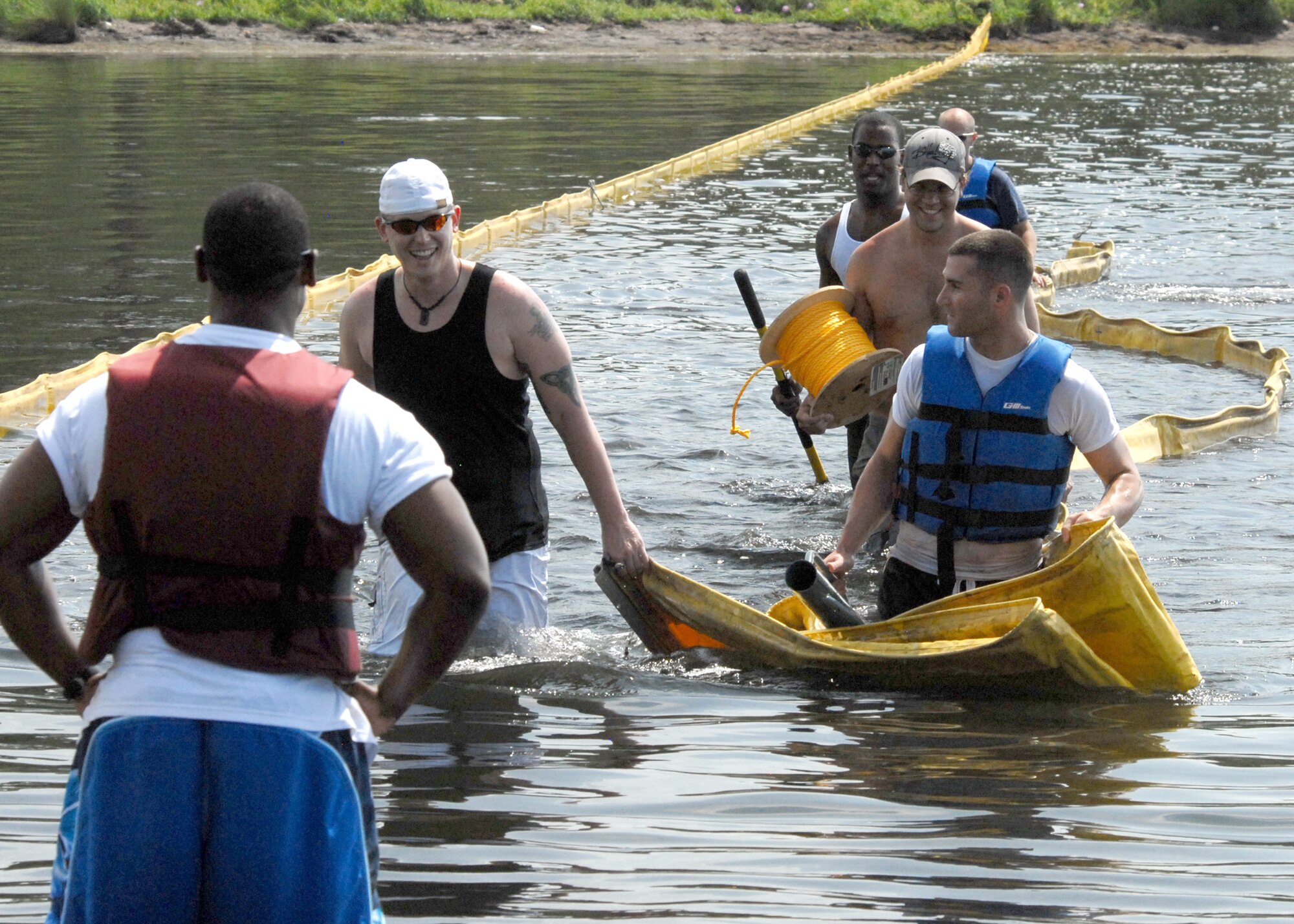 Volunteers bring the towed oil boom into shore prior to installing it along one of many shorelines July 14, 2010, at Eglin Air Force Base, Fla. Boom is an oil containment device used to trap oil in the water so it can be collected before reaching the shore.. (U.S. Air Force photo/Samuel King Jr.) 