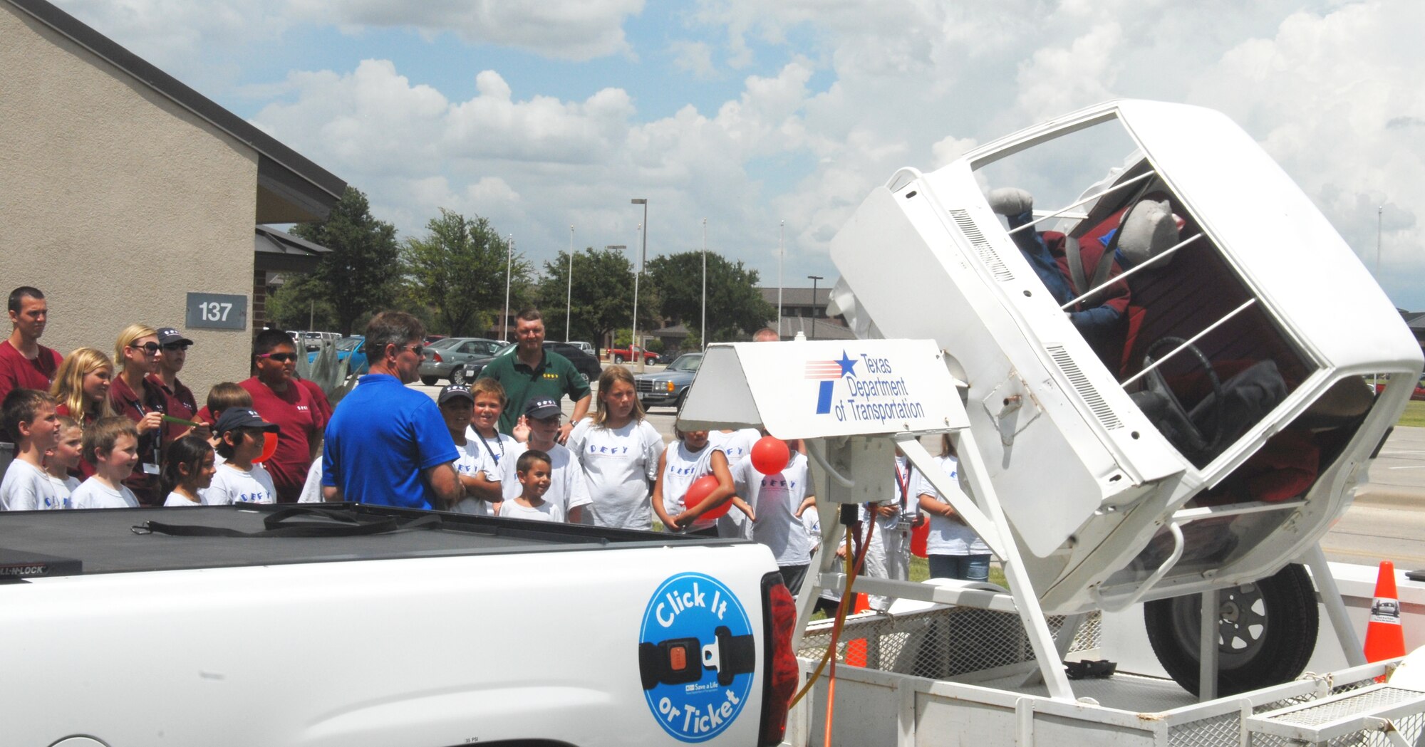 DEFY camp participants and volunteers watch a vehicle rollover demonstration provided by the Texas Department of Transportation July 27. With the use of dummies and the rollover convincer, the group saw what would happen to people involved in a rollover accident while not wearing their seatbelt and then another demonstration while wearing a seatbelt. (U.S. Air Force photo/Connie Hempel)
