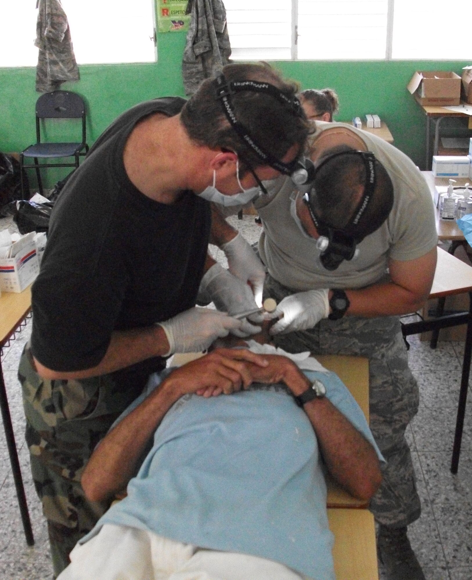 Col. Cliff Zdanowicz and Maj. Lawrence Nguyen, dentists with the Air Force Reserve's 512th Aerospace Medicine Squadron at Dover Air Force Base, Del., team up to perform a tooth extraction on a patient in the Dominican Republic. Thirty-nine 512th AMDS medics provided free medical care to more than 8,000 patients during a medical Readiness Training Exercise July 10-24. (U.S. Air Force photo/Col. Walton Reddish)