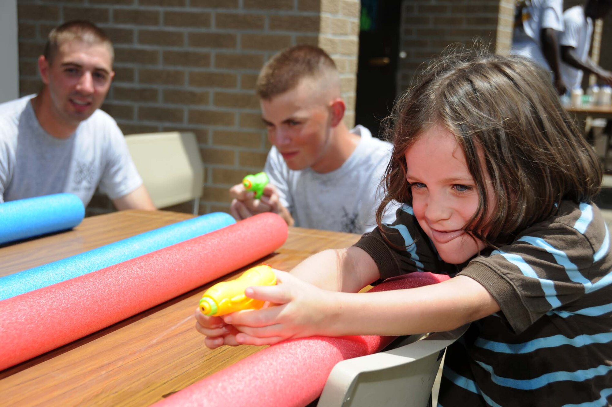 Airman 1st Class Adam Runyan, left, looks on as Airman Basic Jacob Gould and 6-year-old Christian Splain face off in a water gun shoot-off at the conclusion of the summer reading program at Biloxi’s Margaret Sherry Library July 22.  Christian’s parents are Reneé and Shawn Splain of Biloxi.  The Airmen were part of a team of volunteers from the 338th Training Squadron assisting with children’s games at the library along with their squadron chaplain, Chaplain (Capt.) Kenya Thomas.  (U.S. Air Force photo by Kemberly Groue)