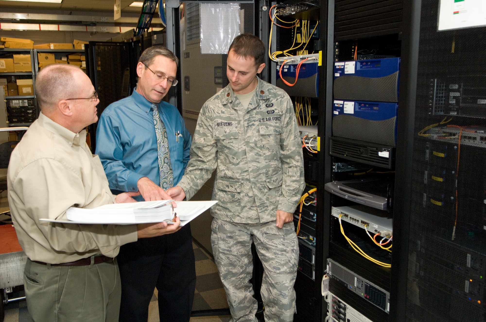 Kent White (left), boundary router modernization project team member, Dennis Murray, web proxy modernization project lead and Maj. Jon Stevens, Network Defense Systems chief, discuss upgrades for the Air Force Network July 23. The Electronic System Center's Cyber/Integration Division recently completed modernization projects to the network which improved capabilities and, in the process, saved the Air Force approximately $24 million. (U.S. Air Force photo by Mark Wyatt)