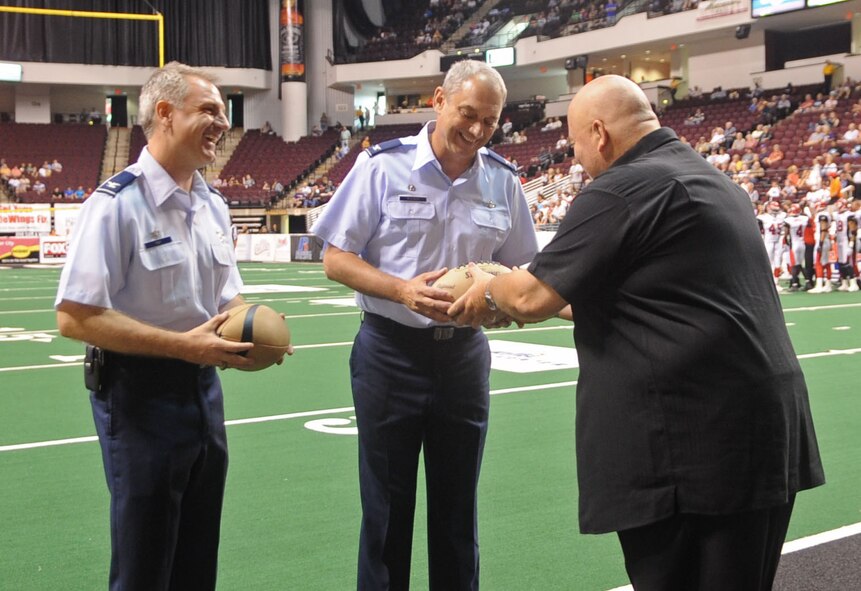 BOSSIER CITY, La. – Sam Newman, Bossier/Shreveport BattleWings, corporate of sales, hands a football to Col. John Mooney III, 917th Wing commander. Col. Timothy Fay, 2d Bomb Wing commander, received his football on the field of the CentryTel Center before the kick-off between the BattleWings and Jacksonville Sharks. July 24 marked Military Appreciation Day. (U.S. Air Force photo by Senior Airman Alexandra M. Boutte) (RELEASED) 