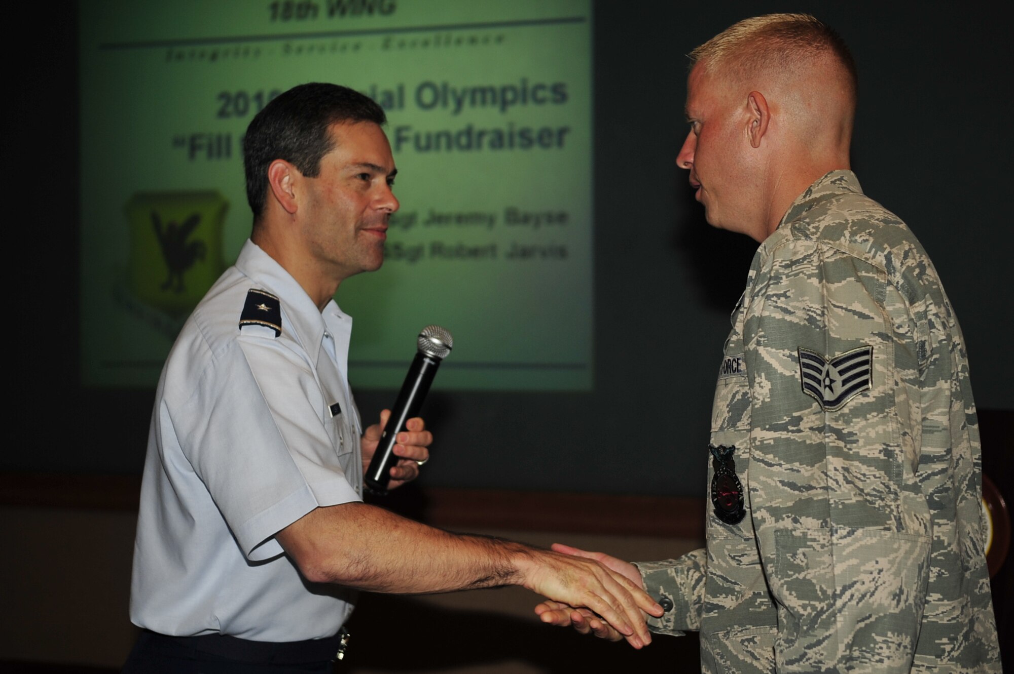 Brig. Gen. Ken Wilsbach, 18th Wing commander presents a coin to Staff Sgt. Jeremy Bayse, 18th Civil Engineer Squadron firefighter, for helping raise more than $22,000 for Kadena Special Olympics during the recent “Fill the Boot” fundraiser. Also honored was Staff Sgt. Robert Jarvis. Kadena Special Olympics will be held this year Nov. 6 on base. (U.S.Air Force photo/Senior Airman Amanda Grabiec)