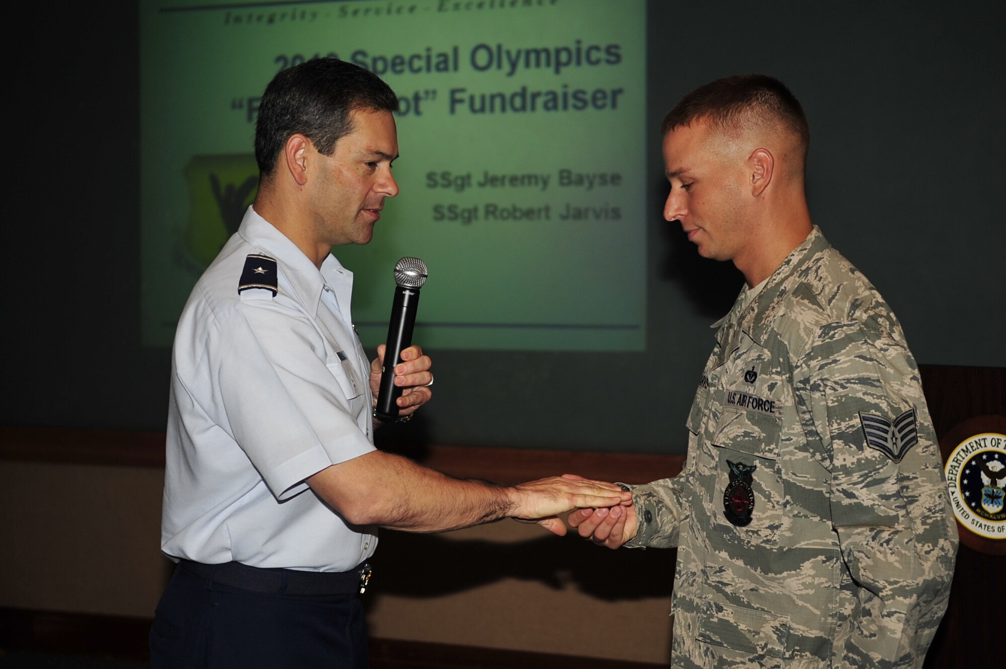 Brig. Gen. Ken Wilsbach, 18th Wing commander, presents a coin to Staff Sgt. Robert Jarvis, 18th Civil Engineer Squadron firefighter, for helping raise more than $22,000 for Kadena Special Olympics during the recent “Fill the Boot” fundraiser. Also honored was Staff Sgt. Jeremy Bayse. Kadena Special Olympics will be held this year Nov. 6 on base. (U.S.Air Force photo/Senior Airman Amanda Grabiec