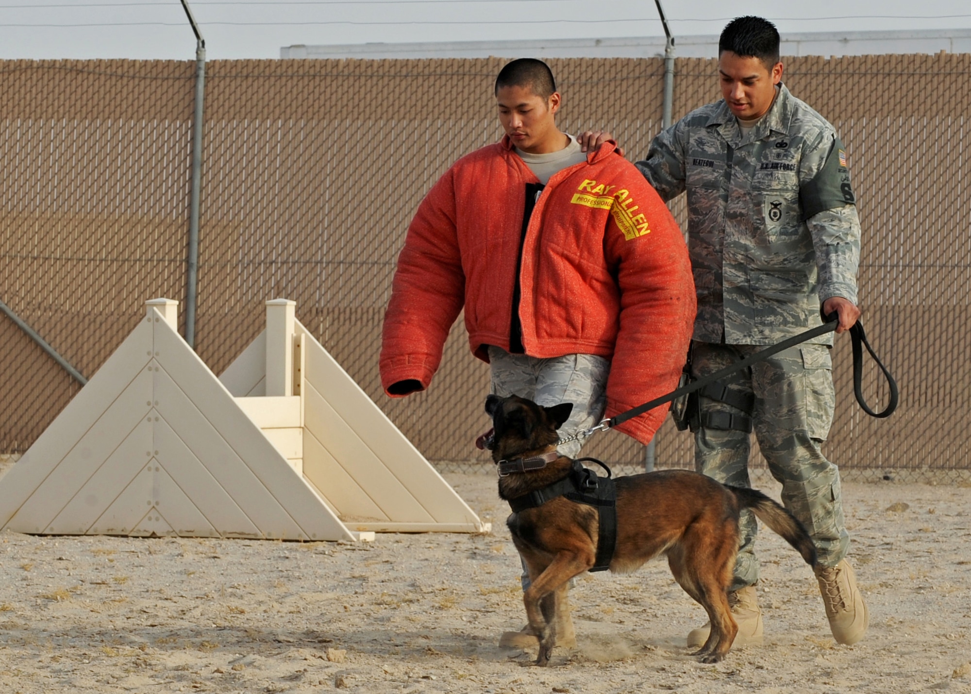 SOUTHWEST ASIA - Staff Sgts. Lino Estacion (left) and Angelo Reategui (right), dog handlers from the 386th Expeditionary Security Forces Squadron, demonstrate the training of a military working dog at an undisclosed air base here July 21, 2010. Each dog is trained to walk in front of its handler and watch for sudden movements. (U.S. Air Force photo by Senior Airman Laura Turner)