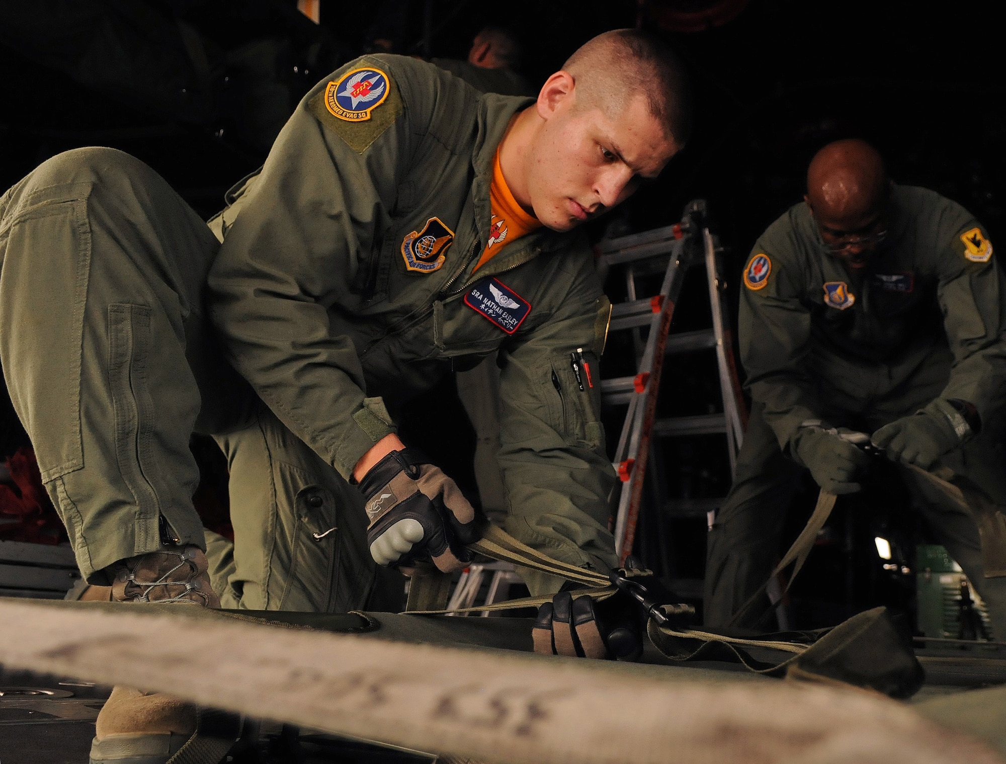 Senior Airman Nathan Easley, 18th Aeromedical Evacuation Squadron flight medic, secures a litter to the side hull of a C-130 in preparation for a bilateral aerovac exchange with the Japan Air Self Defense Force July 23. Airman Easley and other members of the 18th AES spoke to more than 30 JASDF airmen about their mission, equipment and individual responsibilities as the Air Force's only emergency aeromedical care providers in the Western Pacific. (U.S. Air Force photo/Staff Sgt. Jason Lake)