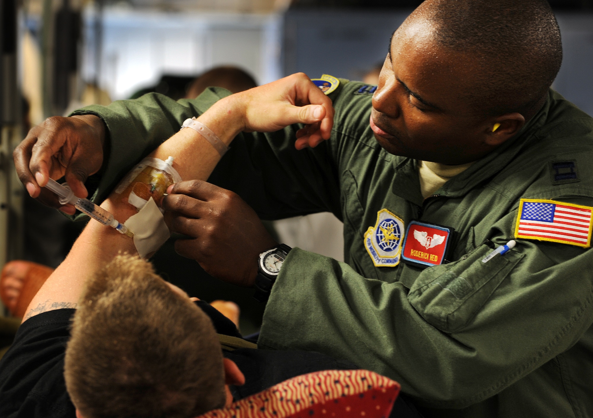 Captain Roderick Reid, a flight nurse from the 775th Expeditionary Aeromedical Evacuation Flight Travis Air Force Base, Calif., administers pain medication to a patient on board a C-17 Globemaster aircraft during a flight from Andrews Air Force Base, Md., on the weekly Integrated Continental United States Medical Operations Plan mission or ICMOP mission as it's known by it's acronym. The mission picks up war wounded and other patients at Andrews AFB and returns them to their homes throughout the United States.   (U.S. Air Force photo by Master Sgt. Rick Sforza)
