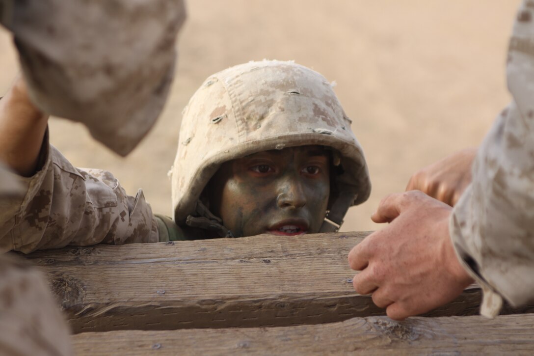Recruit Eduardo Lopez, Platoon 3275, Company M, being helped onto the top platform of the Sky Scraper by two fellow recruits