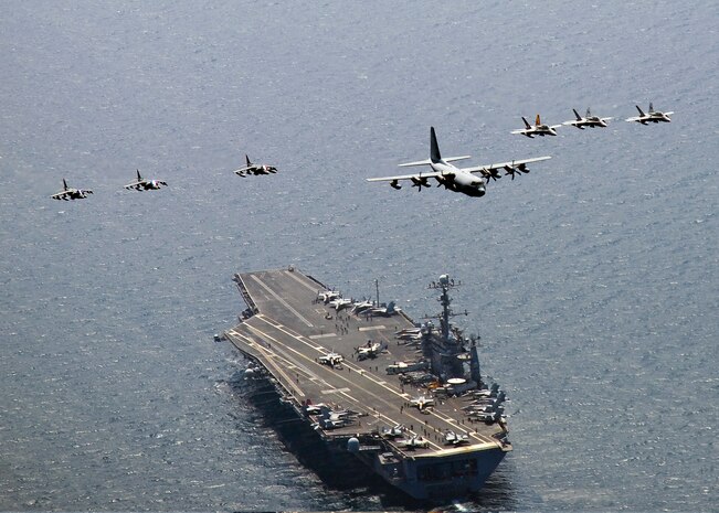 A U.S. Marine Corps C-130 Hercules aircraft, center, leads a formation of three F/A-18C Hornet aircraft, right, and three A/V-8B Harrier aircraft as they fly over USS George Washington (CVN 73) July 27, 2010, while the carrier is under way in the East Sea. George Washington is participating in the combined U.S. and South Korean alliance maritime and air readiness exercise Invincible Spirit. (DoD photo by Mass Communication Specialist 3rd Class Charles Oki, U.S. Navy/Released)