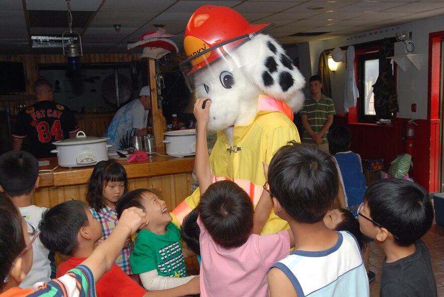 KUNSAN AIR BASE, Republic of Korea -- Sparky the Fire Dog visits with children from the Il Mag Won Orphanage during a Kid’s Day July 24. Sixty-eight children started their 30-day summer vacation off right with the Wolf Pack. The children played games, ate food and went for a swim during their visit. (U.S. Air Force photo/Senior Airman Roy Lynch))