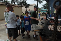 KUNSAN AIR BASE, Republic of Korea -- Children from the Il Mag Won Orphanage watch as Wolf Pack members prepare hot dogs, hamburgers and chicken legs during a Kid’s Day July 24. Sixty-eight children started their 30-day summer vacation off right with the Wolf Pack. The children played games, went for a swim and even met Sparky the Fire Dog. (U.S. Air Force photo/Senior Airman Roy Lynch)