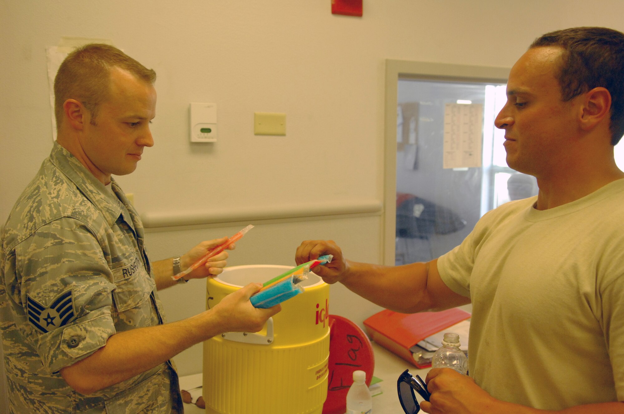 NELLIS AIR FORCE BASE, Nev. -- Staff Sgt. Shane Rushforth, 20th Fighter Wing and Air Expeditionary Wing chaplain assistant, hands a popsicle to Airman 1st Class Taylor Woods, 77th Aircraft Maintenance Unit, for Red Flag 10-4 on July 27, 2010. The chaplain team went around to the various units here during Red Flag passing out drinks and popsicles and chatting with the troops to help boost morale. (U.S. Air Force photo by Airman 1st Class Daniel Phelps)