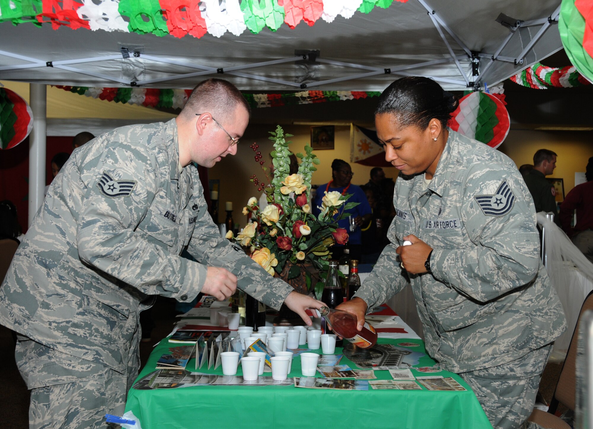 Staff Sgt. Taras Butrej, left, 332nd Training Squadron, and Tech. Sgt. Kristal Dennis, 81st Aerospace Medicine Squadron, pour Italian sodas for sampling at the Italy table, during Diversity Day, July 20 at the Dragon's Lair.  (U.S. Air Force photo by Kemberly Groue)