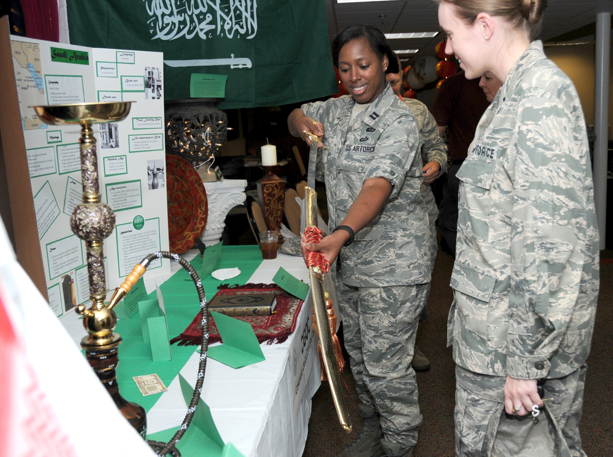 Capt. Christina Hills, 403rd Wing, unsheathes an sword from the Kingdom of Saudi Arabia as 1st Lt. Sarah Reeves, 81st Training Group, looks on at Keesler’s inaugural Diversity Day celebration June 20 at the Dragon’s Lair.  The event showcased art, literature, music and food from cultures around the world.  (U.S. Air Force photo by Kemberly Groue)