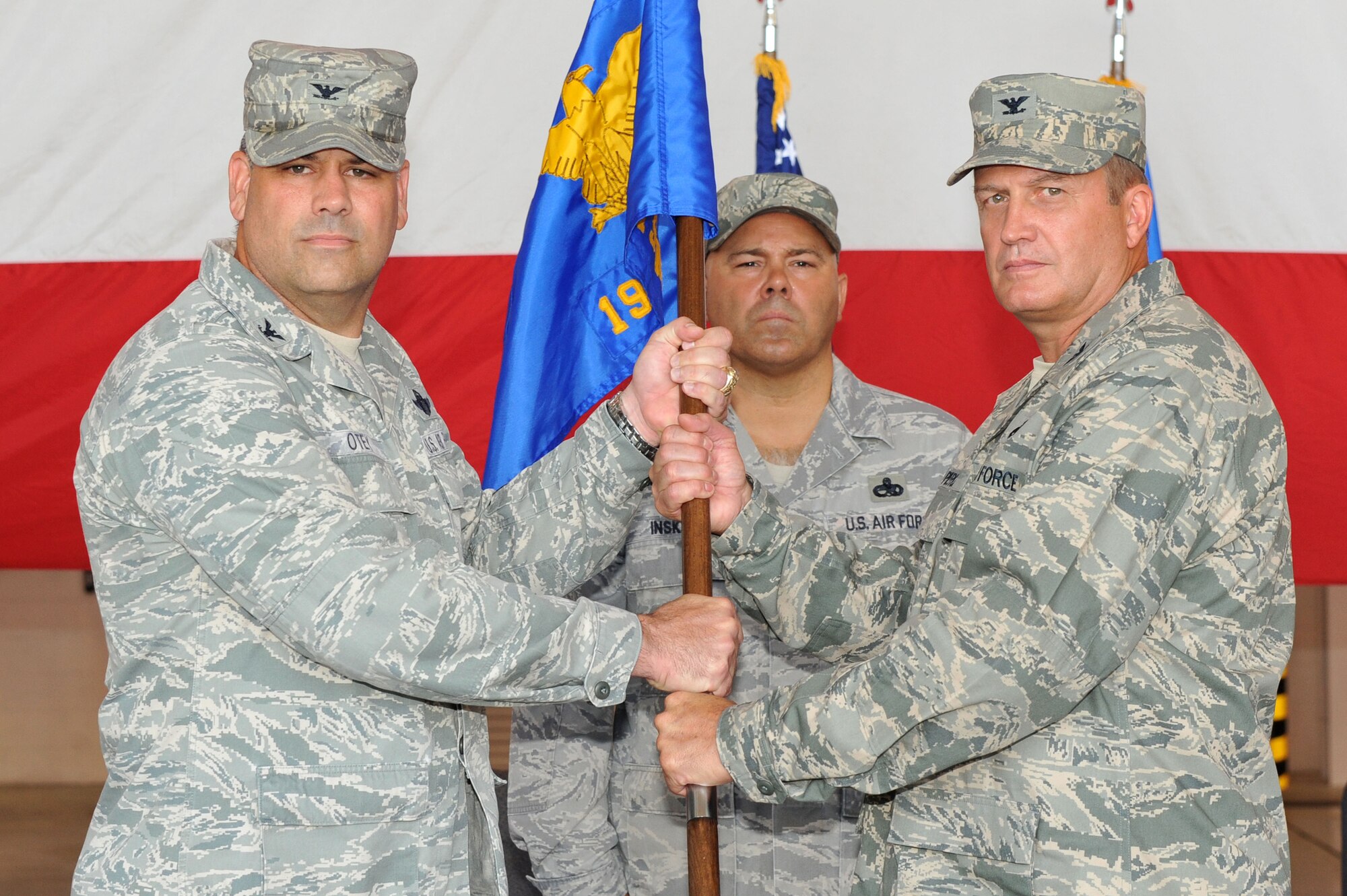 Col. Greg Otey, 19th Airlift Wing commander, passes the 19th Maintenance Group guidon to Col. George Pierce, 19th Maintenance Group commander, during a change of command ceremony July 23 on base. The men and women of the 19th AW and Little Rock Air Force Base bid farewell to Colonel Christopher Hair and welcome Colonel Pierce and his family to the Black Knight team. (U.S. Air Force photo by Senior Airman Steele C. G. Britton)