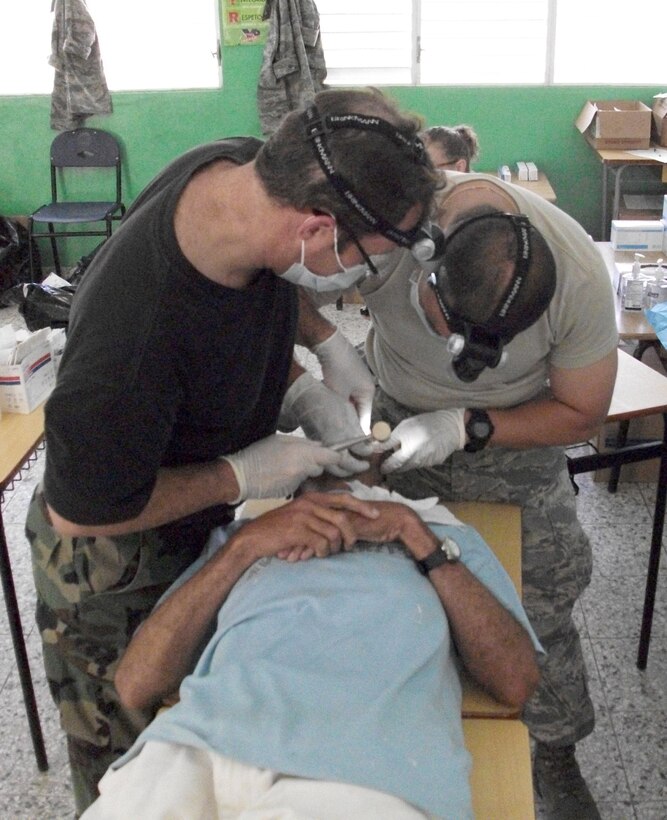 Col. Cliff Zdanowicz and Maj. Lawrence Nguyen team up to perform a tooth extraction on a patient July 22, 2010, in the Dominican Republic. Thirty-nine medics provided free medical care to more than 8,000 patients during a Medical Readiness Training Exercise July 10 through 24, 2010. Colonel Zdanowicz and Major Nguyen are dentists with the Air Force Reserve's 512th Aerospace Medicine Squadron at Dover Air Force Base, Del. (U.S. Air Force photo/Col. Walton Reddish)