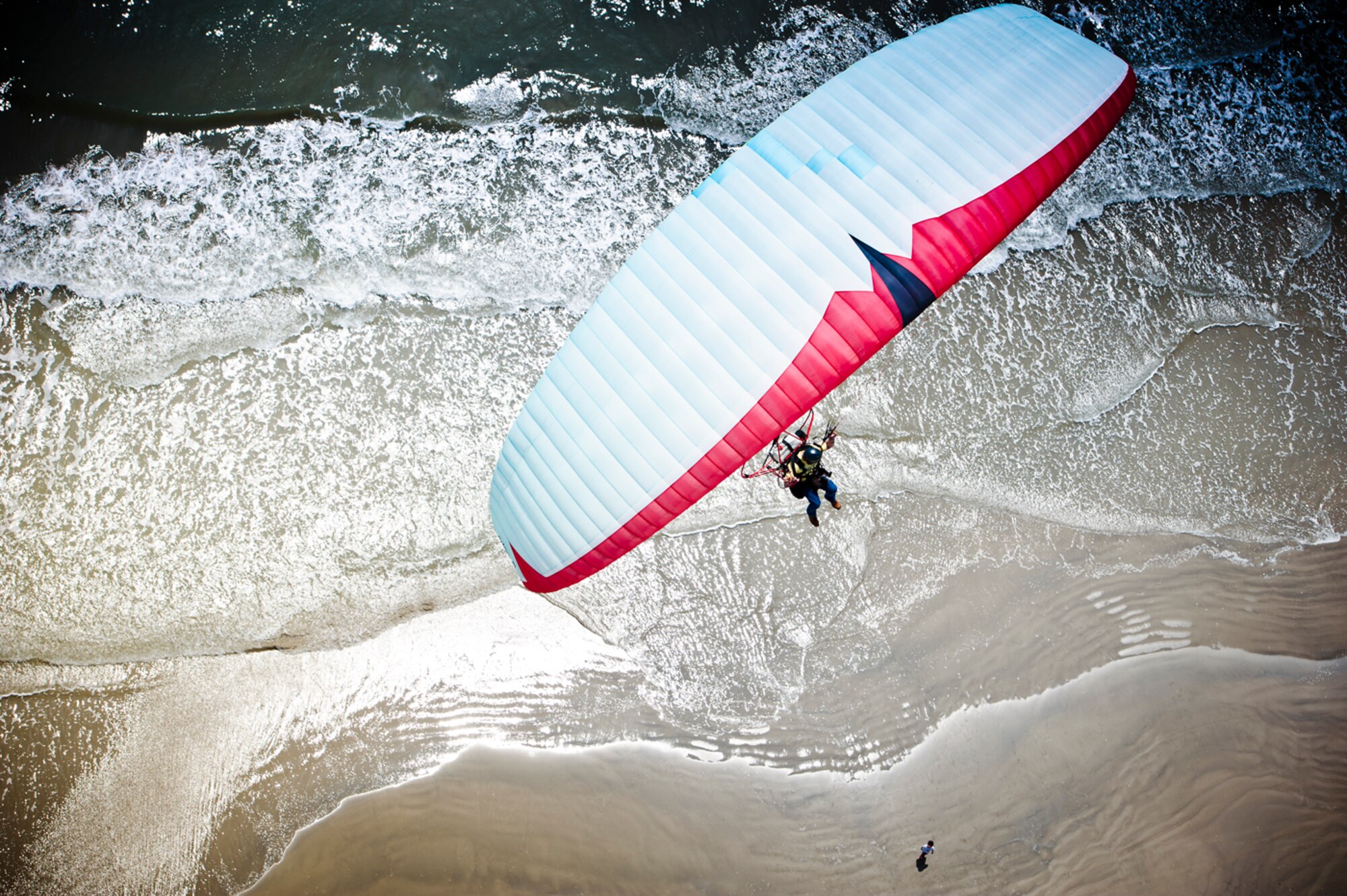A Narrow Escape - Soaring over the Gulf of Mexico off the shores of Galveston, Texas, a powered parachutist prepares to land near the scene that nearly claimed the life of one of his brethren. (photo by Tech. Sgt. Samuel Bendet)
