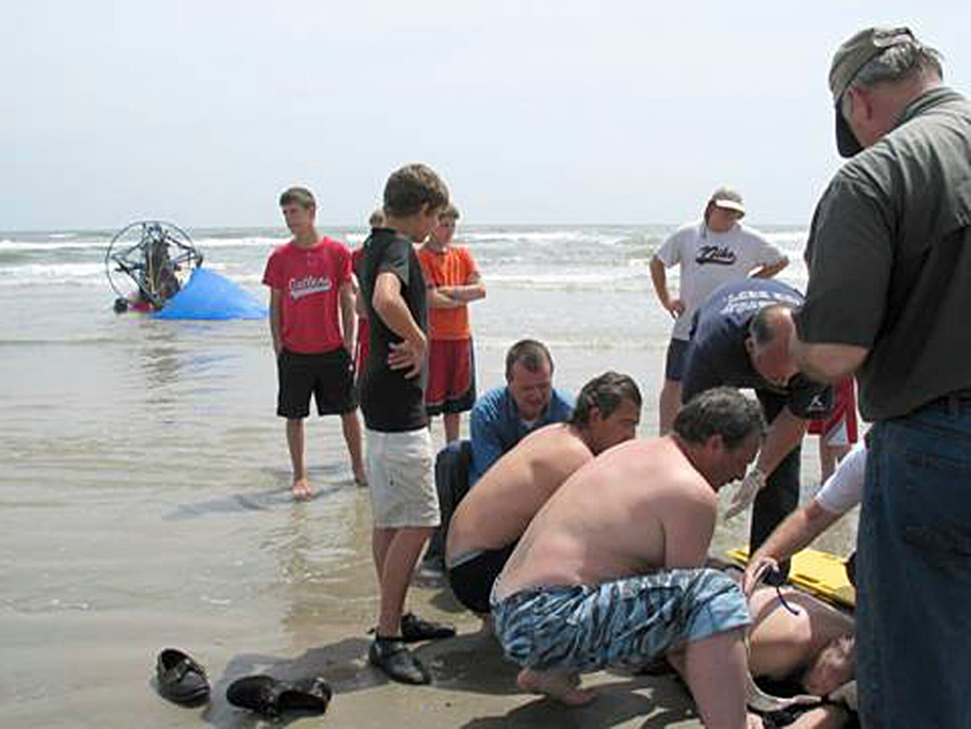 A Narrow Escape - Rescue workers and Good Samaritans provide first aid to Ken Harger, who was not breathing after they freed him from his crashed aerial vehicle. CPR revived him that fateful Good Friday afternoon, allowing him, after a short hospital stay, to return home Sunday in time for Easter dinner with his family. (photo by Chris Page)
