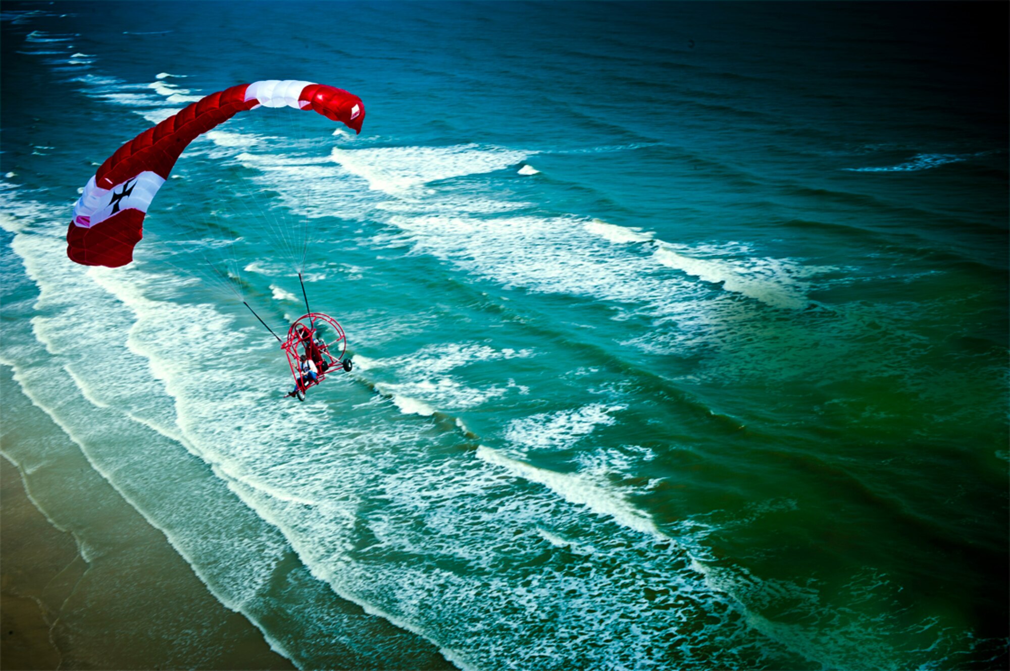 A Narrow Escape - Soaring over the Gulf of Mexico off the shores of Galveston, Texas, a powered parachutist prepares to land near the scene that nearly claimed the life of one of his brethren. (photo by Tech. Sgt. Samuel Bendet)
