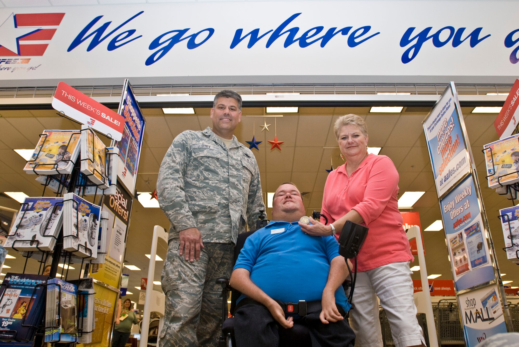 Col. Greg Otey, 19th Airlift Wing commander, presents a coin July 27 to John Perry, Army and Air Force Exchange Service store associate, and his mother, Nelda, for his selection as the Combat Airlifter of the Week. Mr. Perry received the "Outstanding Associate with Disability Award" for the central region in 2002. (U.S. Air Force photo by Staff Sgt. Nestor Cruz)