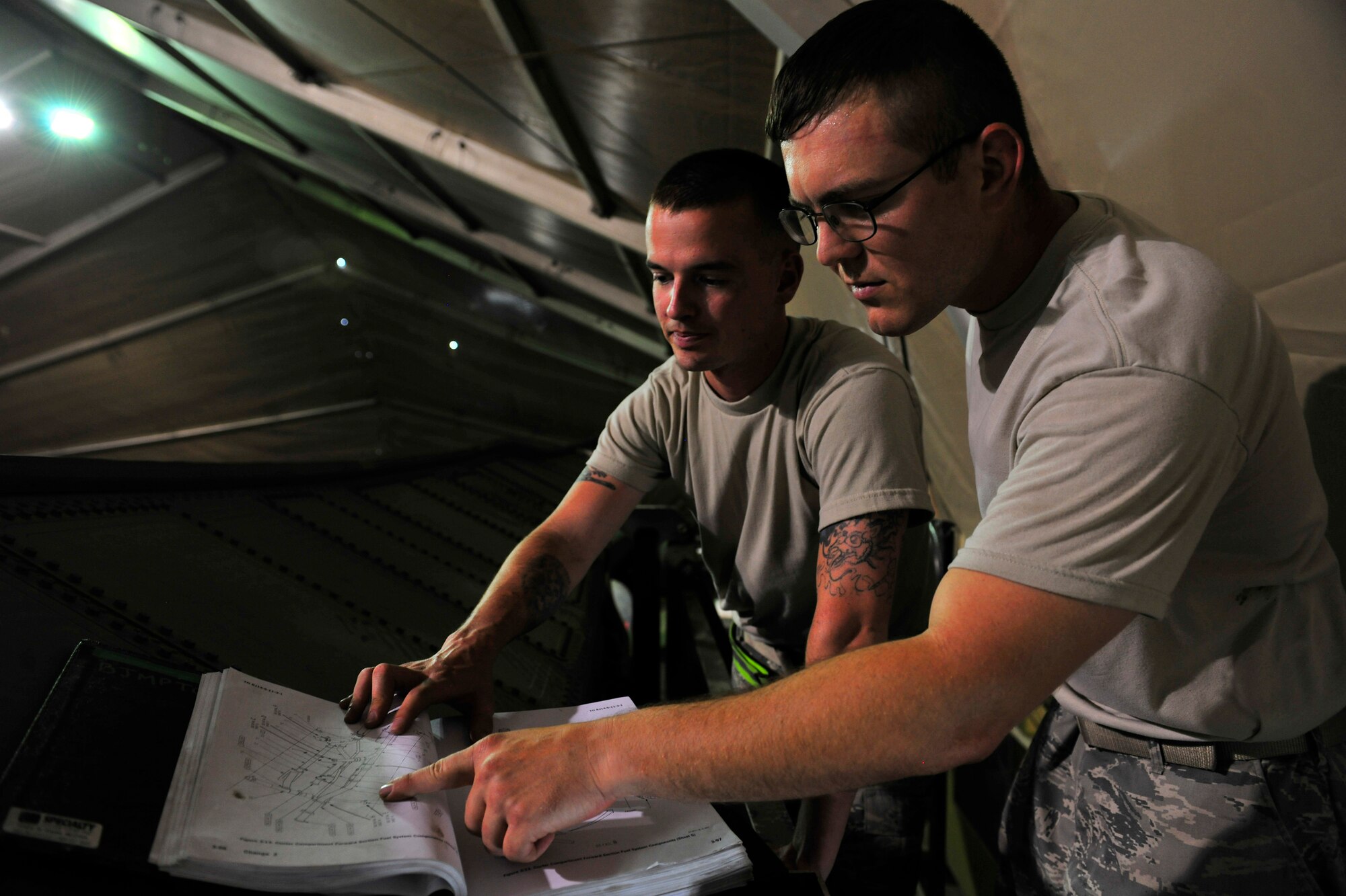Left to right: Staff Sgt. Michael Teague and Senior Airman Ryan Houts, aircraft fuel systems repair journeymen assigned to the 455th Expeditionary Aircraft Maintenance Squadron, look at a technical order of a refuel schematic for a safety pressure lead valve on a conformal fuel tank designed for an F-15E Strike Eagle at Bagram Airfield, Afghanistan, July 27, 2010. (U.S. Air Force photo/Staff Sgt. Christopher Boitz)