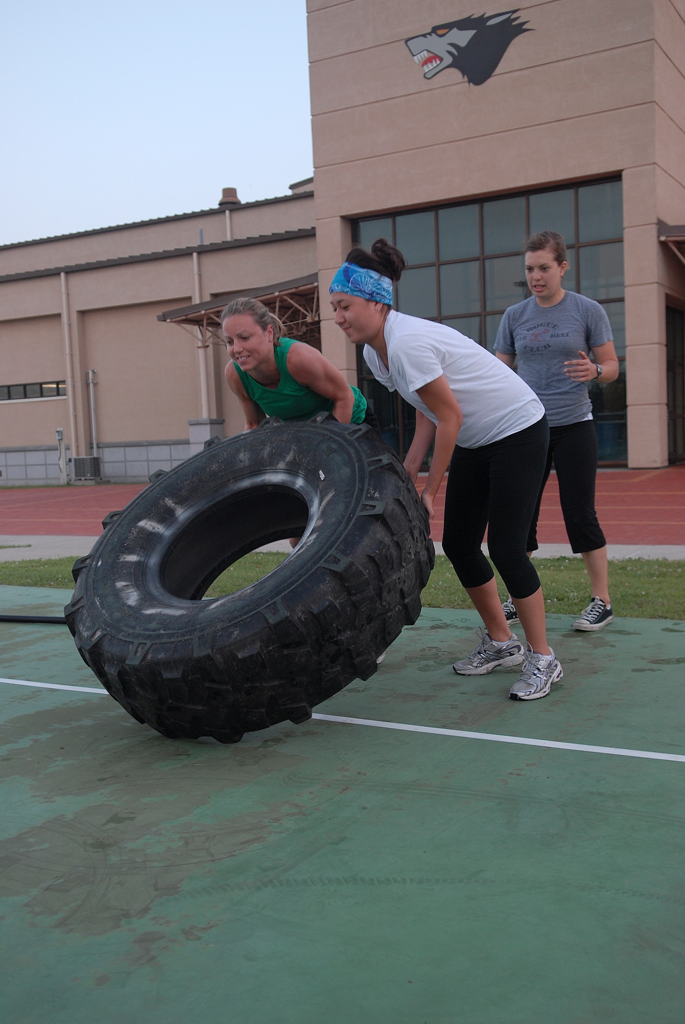 KUNSAN AIR BASE, Republic of Korea -- Capt. Melissa Thurman, 8th Fighter Wing, and 1st Lt. Fiona Dailey, 8th Fighter Wing, flip a tire, while 1st Lt. Kari Kundert, 8th Operation Group, keeps watch for safety and proper form during a CrossFit workout July 27. CrossFit combines aerobic workouts with strength training to increase strength, flexibility, agility and endurance. (U.S. Air Force photo/Senior Airman Roy Lynch)
