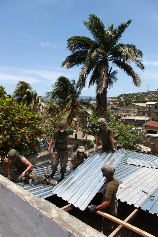 Marines with 8th Engineer Support Battalion, Logistics Combat Element of Special-Purpose Marine Air-Ground Task Force Continuing Promise 2010 work together to install sheet metal on a hospital roof in Port-de Paix, Haiti, July 29, 2010. CP10 is a collaborative effort that involves military and civilian personnel providing humanitarian assistance and disaster relief to the Caribbean, Central and South America.