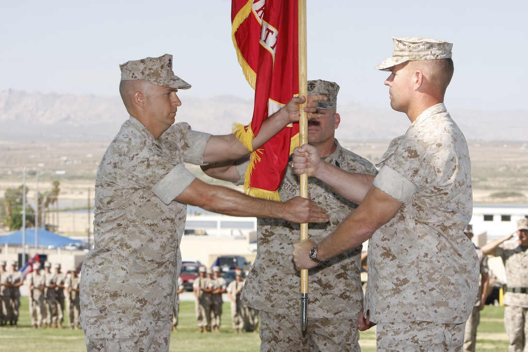 Lieutenant Col. Tom Gordon [right], transfers the unit colors and command of 1st Tank Battalion to Lt. Col. Timothy Barrick during a change of command ceremony at Lance Cpl. Torrey L. Gray Field July 29. Gordon is returning to his hometown of Boston to serve as the security fellow for the Massachusetts Institute of Technology.