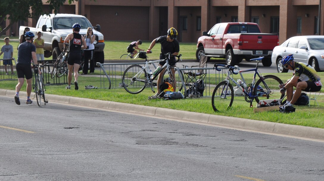 The first few cyclists to finish the bike portion of the mini-biathlon hustle to put their bikes up and change shoes before starting the running portion of the competition July 24, at Sheppard Air Force Base, Texas. The biathlon consisted of a 20K bike ride and a 5K run. Competitors were categorized in by age ranging from older than 40 to younger than 16. (U.S. Air Force photo/Airman 1st Class Adawn Kelsey)