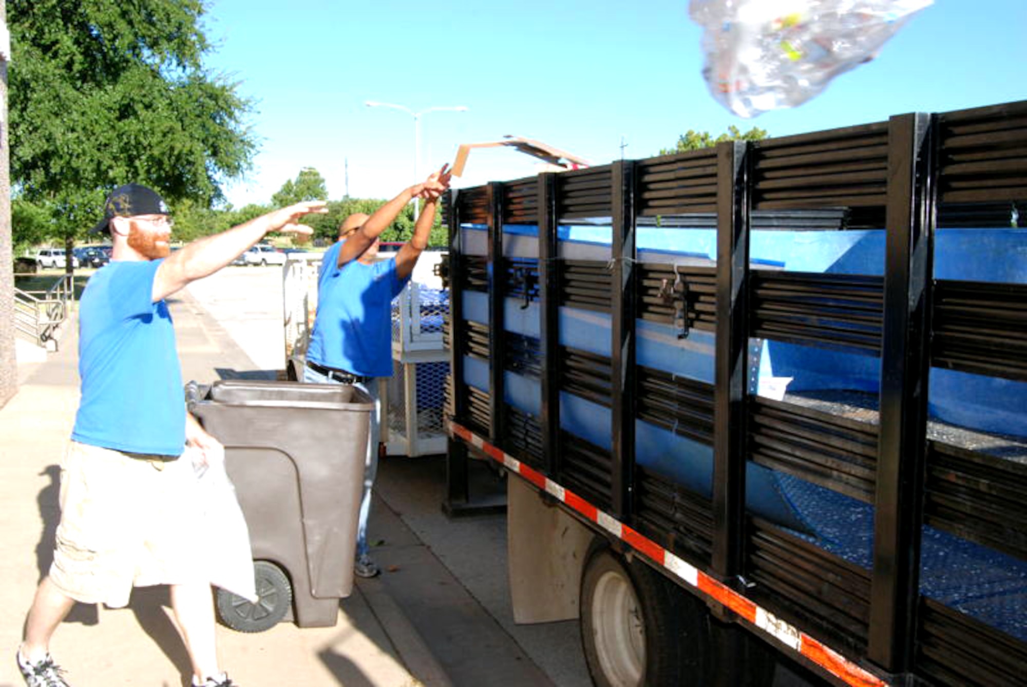 Jimmy Snyder, left, and John Spooner throw bags of recyclable materials in the back of a truck July 29 as they make their rounds on Sheppard Air Force Base, Texas. By simply recycling materials on base, permanent party and student units can win a $1,000 cash award for participating in the program. (U.S. Air Force photo/Mike McKito)