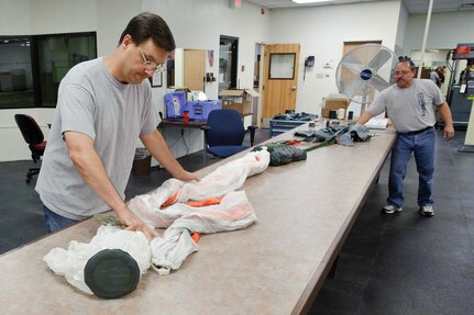 Howard Sharrot and Dave Amaya with the 12th Operational Support Squadron aircrew flight equipment shop unpack a B-22 parachute, used by T-38 pilots, during a six month safety inspection at Randolph Air Force Base July 15.  (U.S. Air Force photo/Steve Thurow)