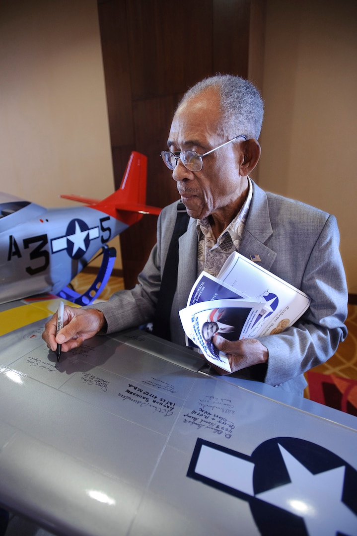 Booker Conley signs a P-51 Mustang model at the 39th Tuskegee Airmen convention July 29. Mr. Conley was in the civil pilot training program at the Tuskegee Institute in 1940.  As an ROTC graduate he and went on to serve in the infantry with the 92nd Buffalo Division in Italy during World War II. (U.S. Air Force photo/Steve Thurow) 