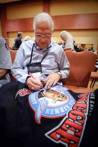 Dr. Thurston Gaines signs a Tuskegee Airmen jacket following the opening of the 39th Tuskegee Airmen convention held in downtown San Antonio, Texas. Dr. Gaines was a P-51 pilot with the 99th Fighter Squadron and became a POW in Germany during the war. He was treated fairly when in captivity but ignored by his fellow prisoners once liberated. (U.S. Air Force photo/Steve Thurow)