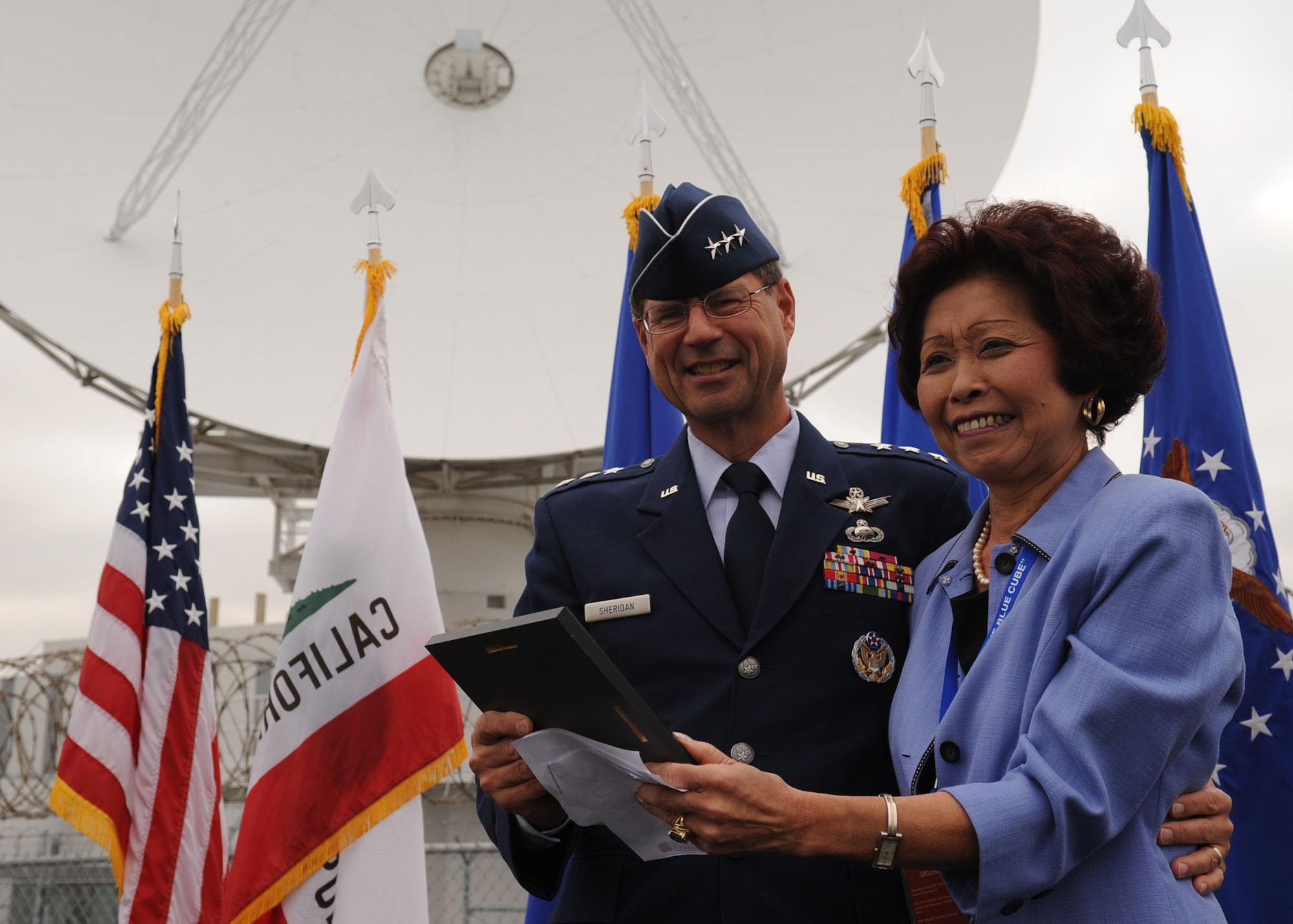 SUNNYVALE, Calif.-- Lt. Gen. John T. Sheridan, commander of the Space and Missile Center, Los Angeles Air Force Base, presents Lorna Onizuka, widow of Col. Ellison Onizuka, astronaut aboard the Space Shuttle Challenger disaster, with a commemorative plaque during a closure ceremony for Onizuka Air Force Station here, Wednesday, July 28, 2010. Built in 1960, Onizuka AFS was originally known as the Air Force Satellite Test Center. It was selected for closure by the Base Closure and Realignment Commission in 2005, with the recommendation to move operations to Vandenberg Air Force Base, in order to consolidate satellite command and control operations while reducing excess infrastructure.  (U.S. Air Force Photo/Senior Airman Bryan Boyette)