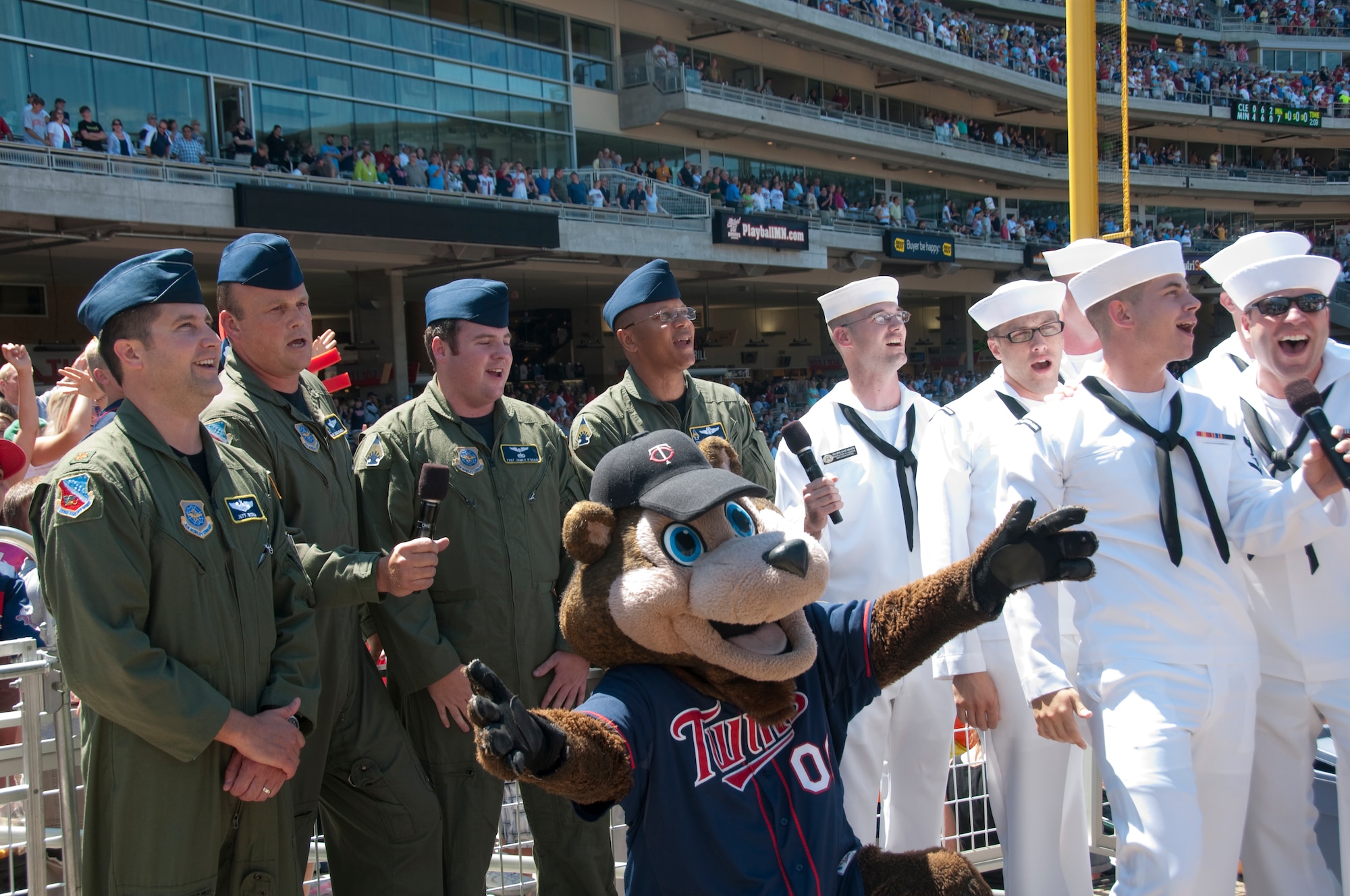 The Air National Guard air crew who dropped the U. S. Navy "Leap Frogs" parachute team from a 133rd Airlift Wing C-130, joins a group of Sailors in the seventh inning stretch singing at Target Field on July 21, 2010. The Minnesota Twins are celebrating Navy Day in their new stadium.  USAF official photo by Captain Ann Todd