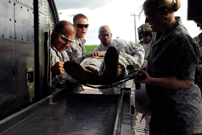 SOTO CANO AIR BASE, Honduras --  Tech. Sgt. Jeffrey Gray (left), Staff Sgt. Travis Smith, Master Sgt. Sean Gathers and Senior Airman Megan Wharton, all of the Medical Element here, load a "patient" onto a helicopter with the guidance of Staff Sgt. Shontal Thompson, a 1-228th Aviation Regiment flight medic, here July 27. The MEDEL recently had more than a 90 percent turn-over in personnel, which necessitated an updated class. (U.S. Air Force photo/Tech. Sgt. Benjamin Rojek)