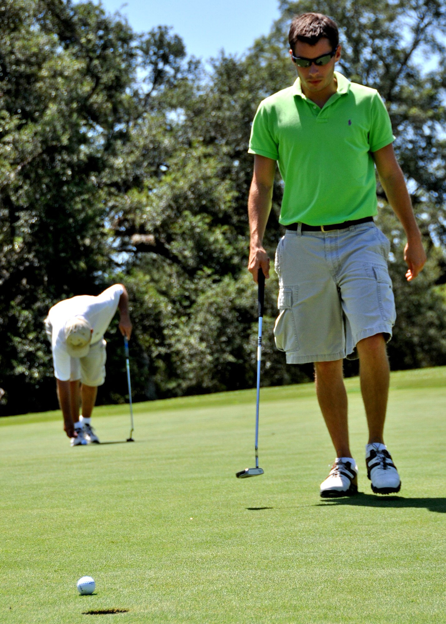 Ryan Decker, Air Force Research Lab, walks toward his ball as teammate Dave Onuffer, begins to line up his putt during the base intramural golf championship July 28 at the Eglin golf course.  Perennial rivals, Air Force Research Lab and 53rd Wing, faced off in the championship match, with AFRL winning 8-4.  The AFRL team has claimed the base title three years straight.  (U.S. Air Force photo/Tech Sgt. Cheryl Foster)
