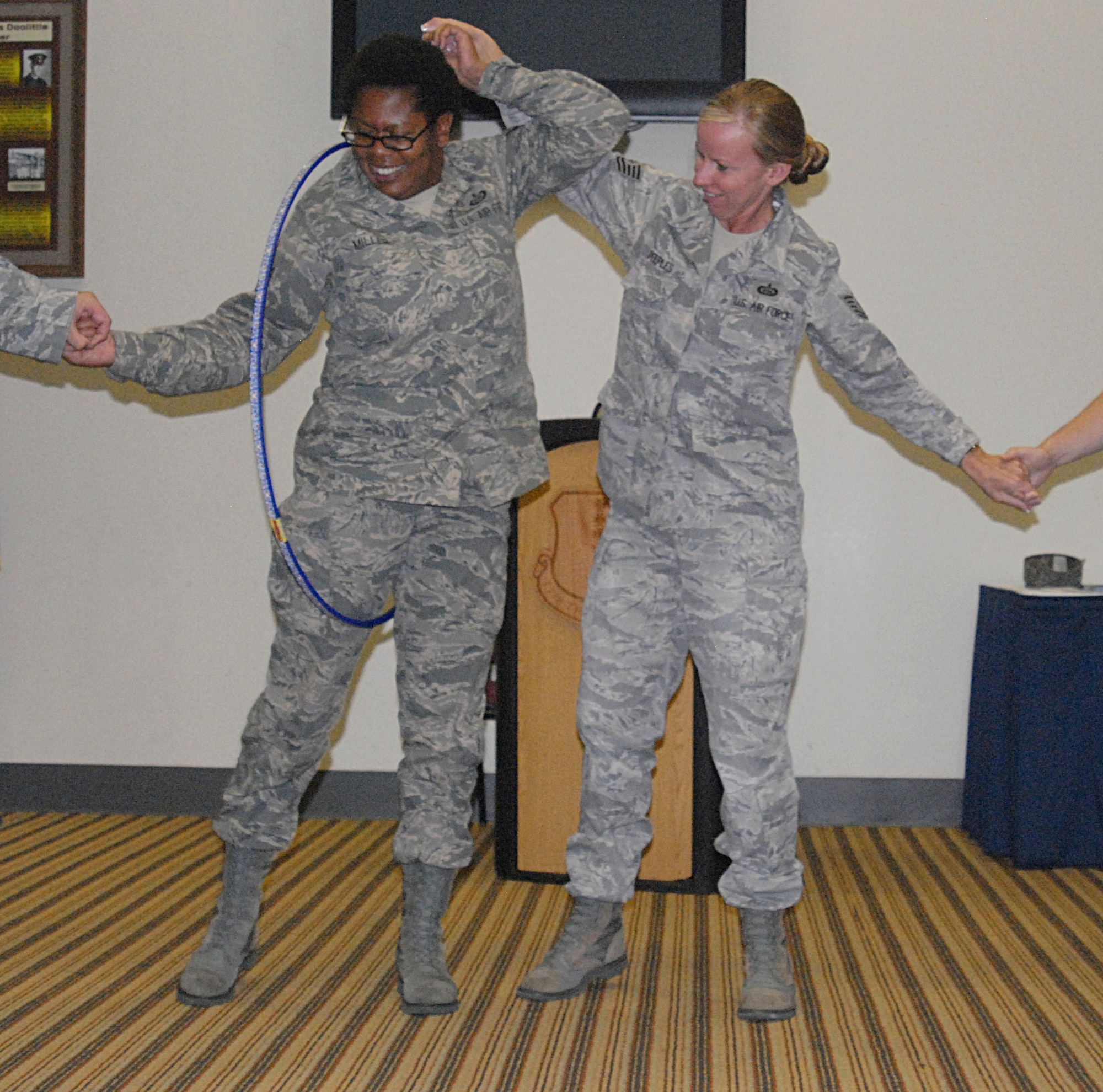 From left: Tech. Sgt. Erica Miller, 316th Training Squadron, and Tech. Sgt. Ina Peeples, 315th Training Squadron, try to manuever a hula hoop around the circle without letting go of each other. This was a team building exercise 18 technical sergeants participated in during the Senior NCO course here July 26-29. (U.S. Air Force photo/Connie Hempel)